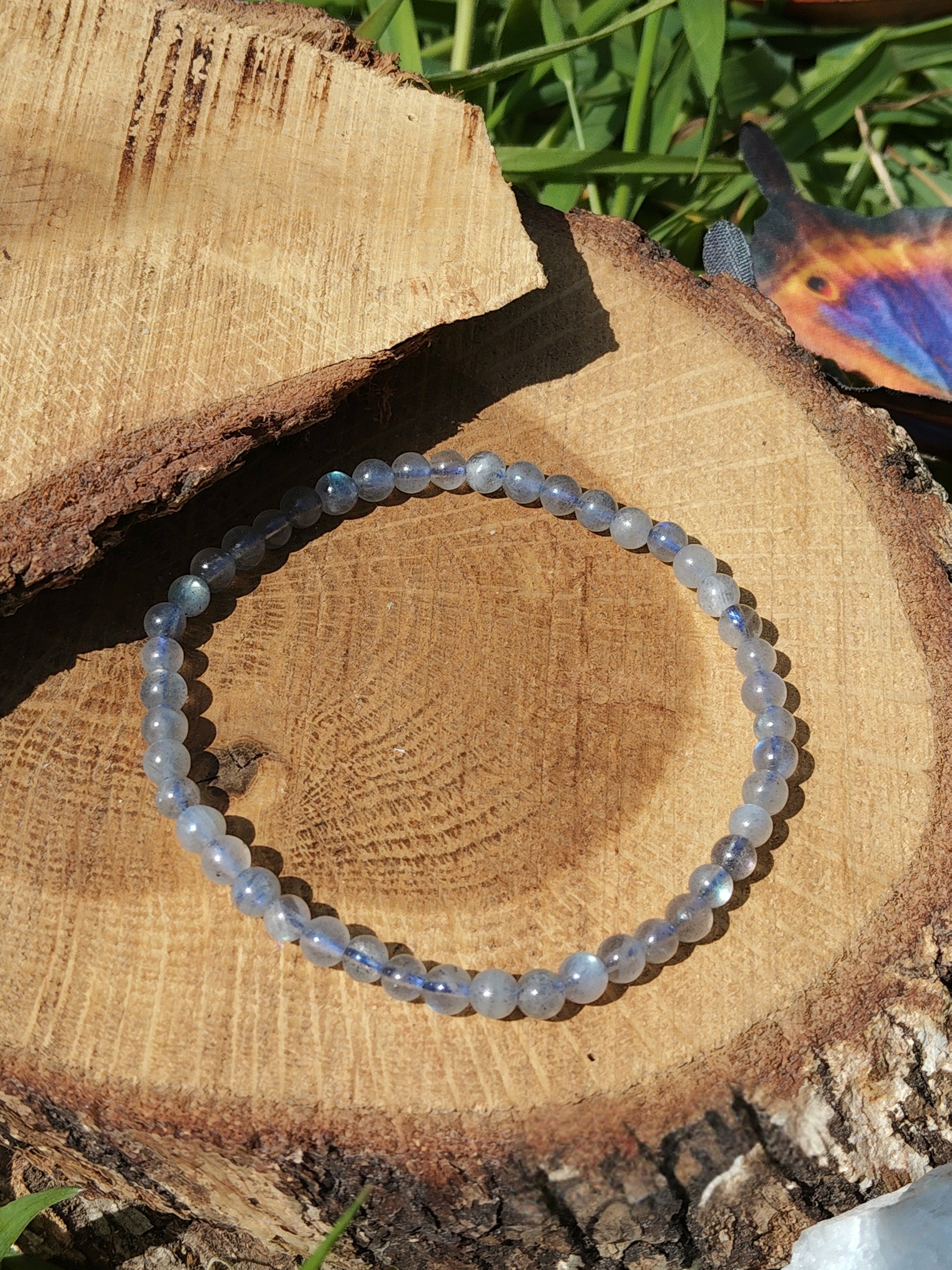 Bracelet labradorite 4 mm sur grande tranche de bois clair, perles gris argenté et reflets bleu froid, présence, recul émotionnel et ancrage doux
