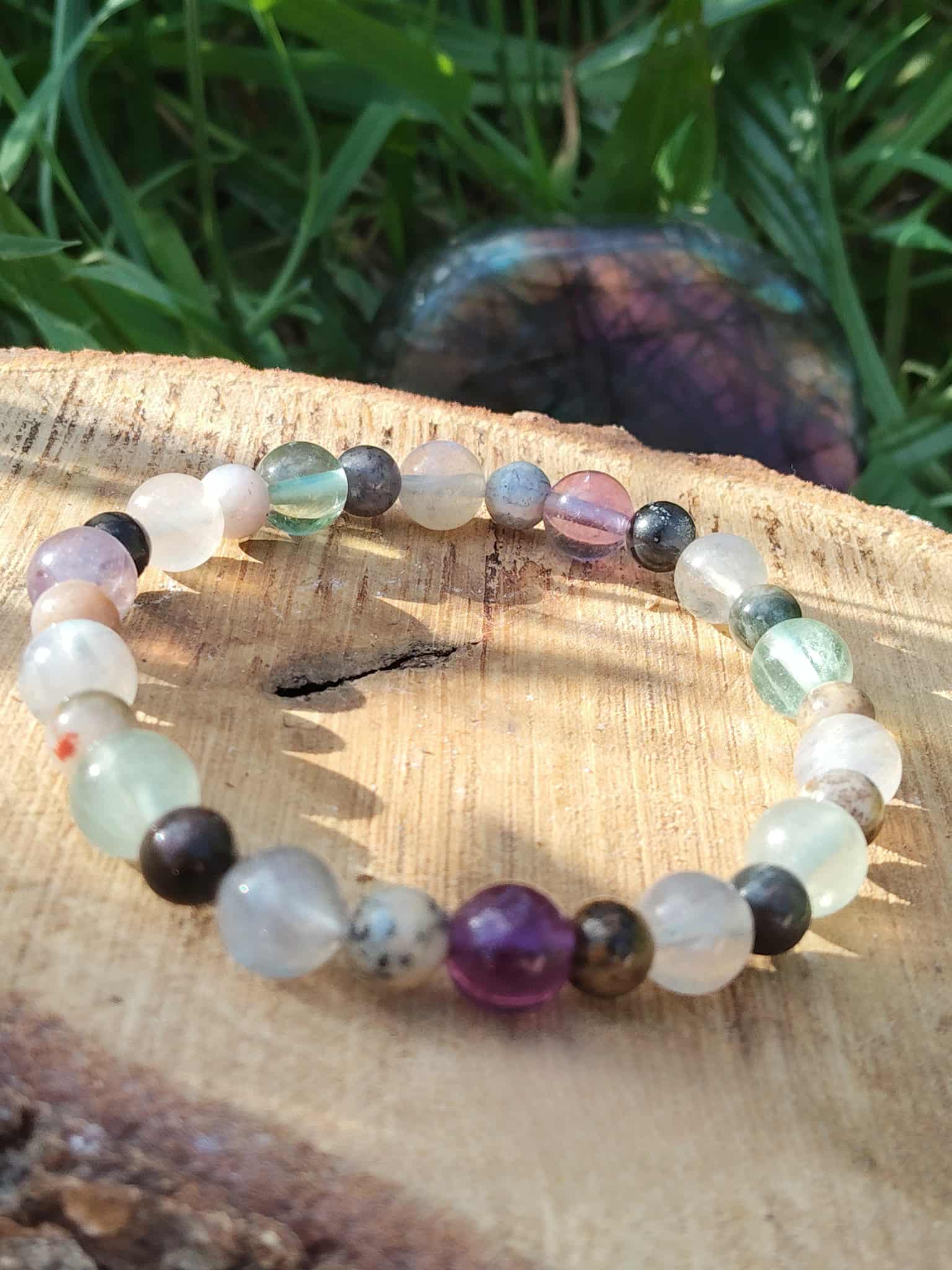 Bracelet 3e œil posé sur rondin de bois avec herbe, pierres naturelles pour ouverture du chakra Ajna et mémoire onirique