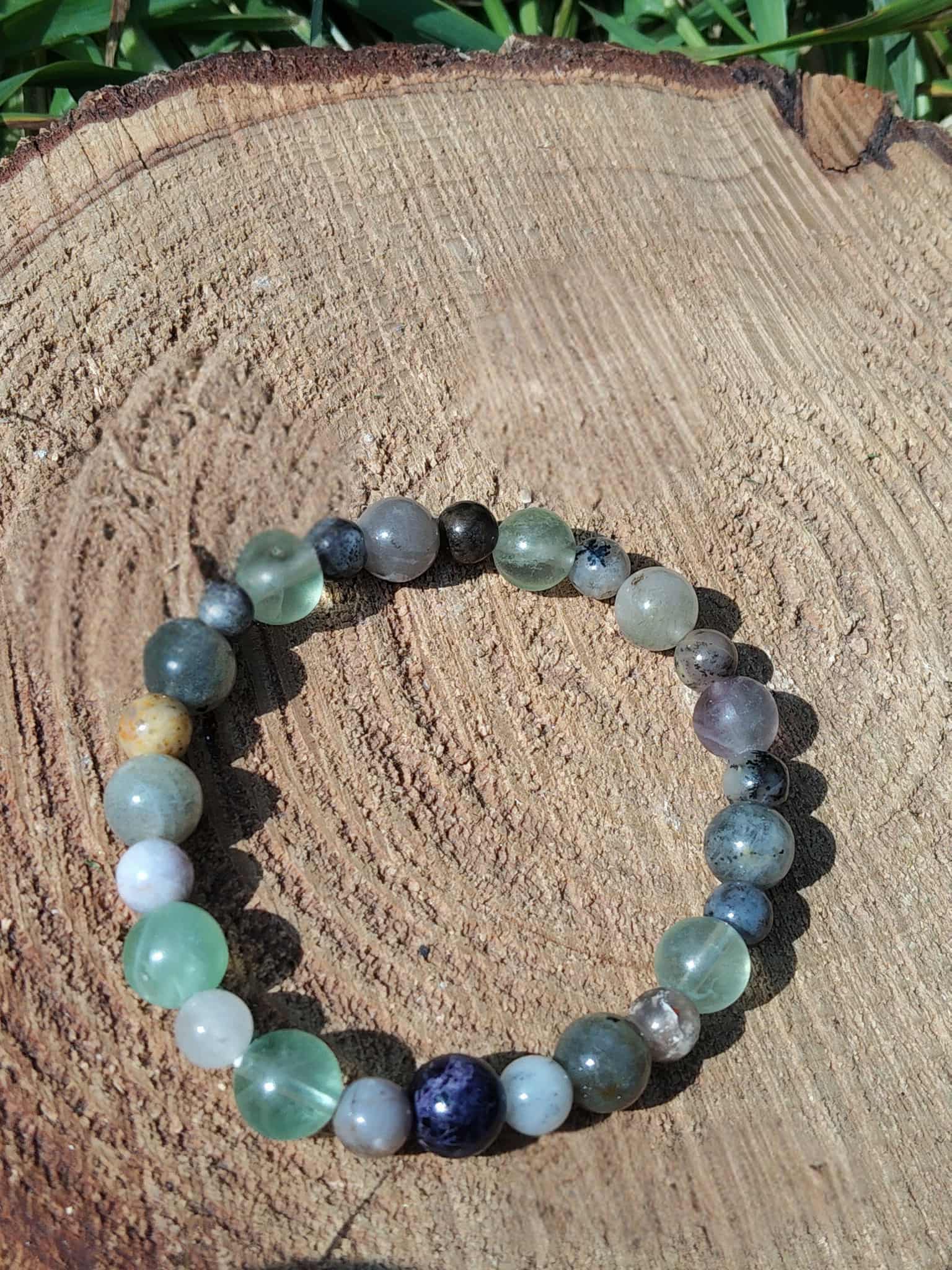 Bracelet chakra Ajna sur bois clair avec herbe en arrière-plan, perles naturelles pour discernement, intuition et esprit apaisé