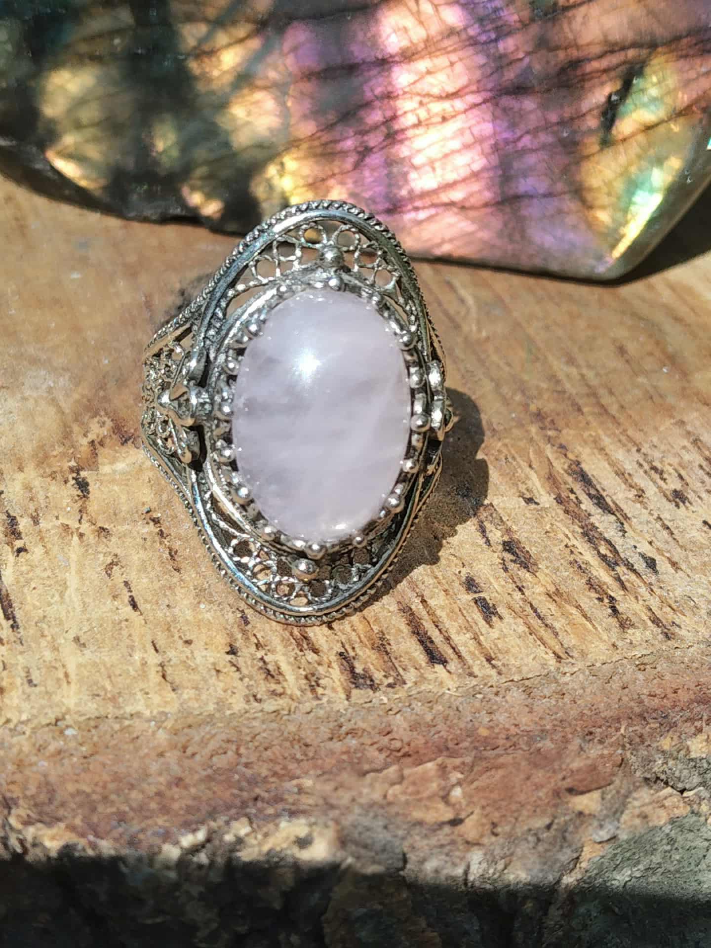 Bague en quartz rose monture en argent 925 posée sur du bois, lumière naturelle aux nuances pastel, ambiance douce et apaisante évoquant amour, tendresse et harmonie du cœur