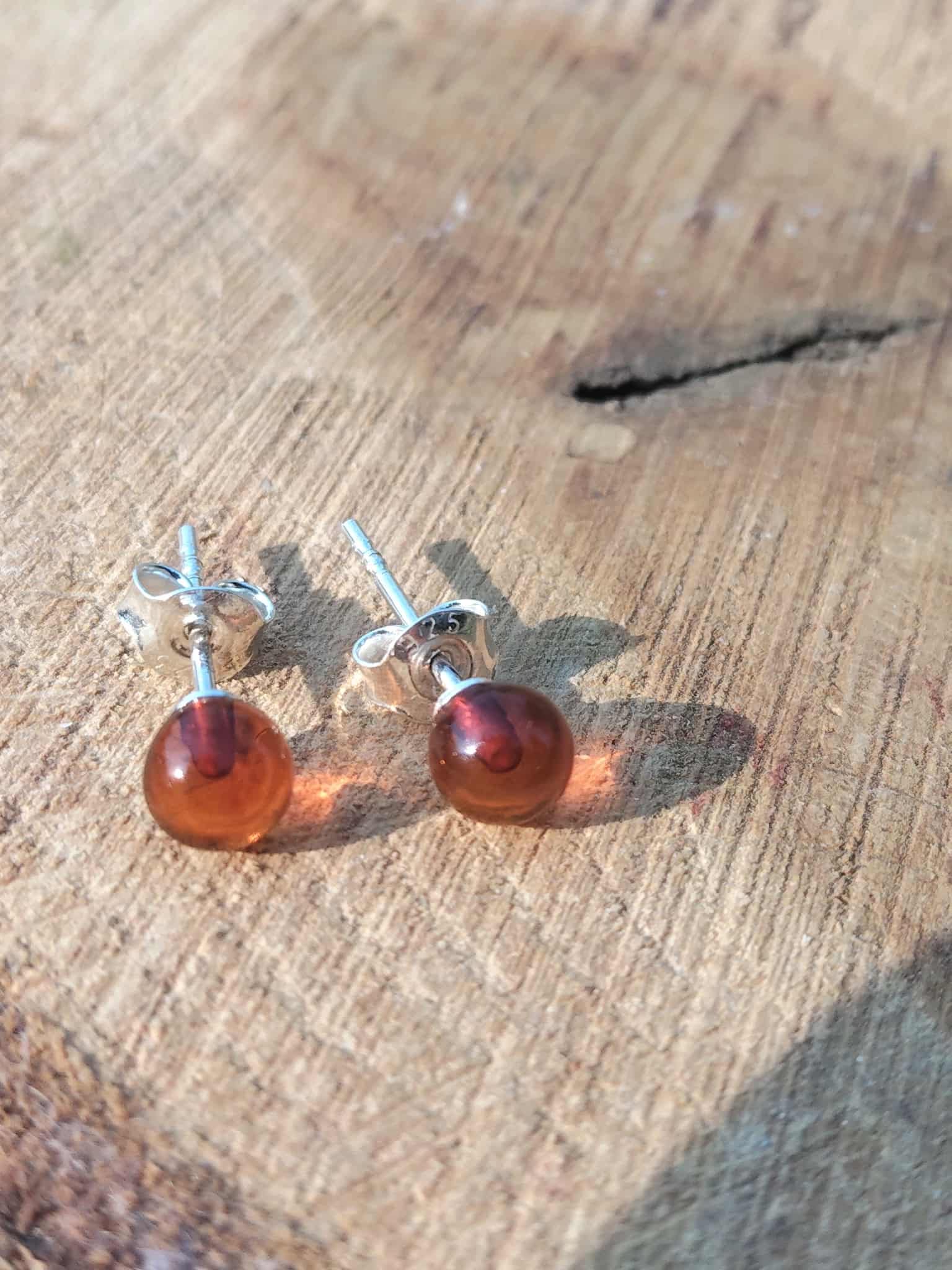 Boucles puces ambre cognac en argent 925 posées sur tissu en lin – énergie solaire, vitalité.