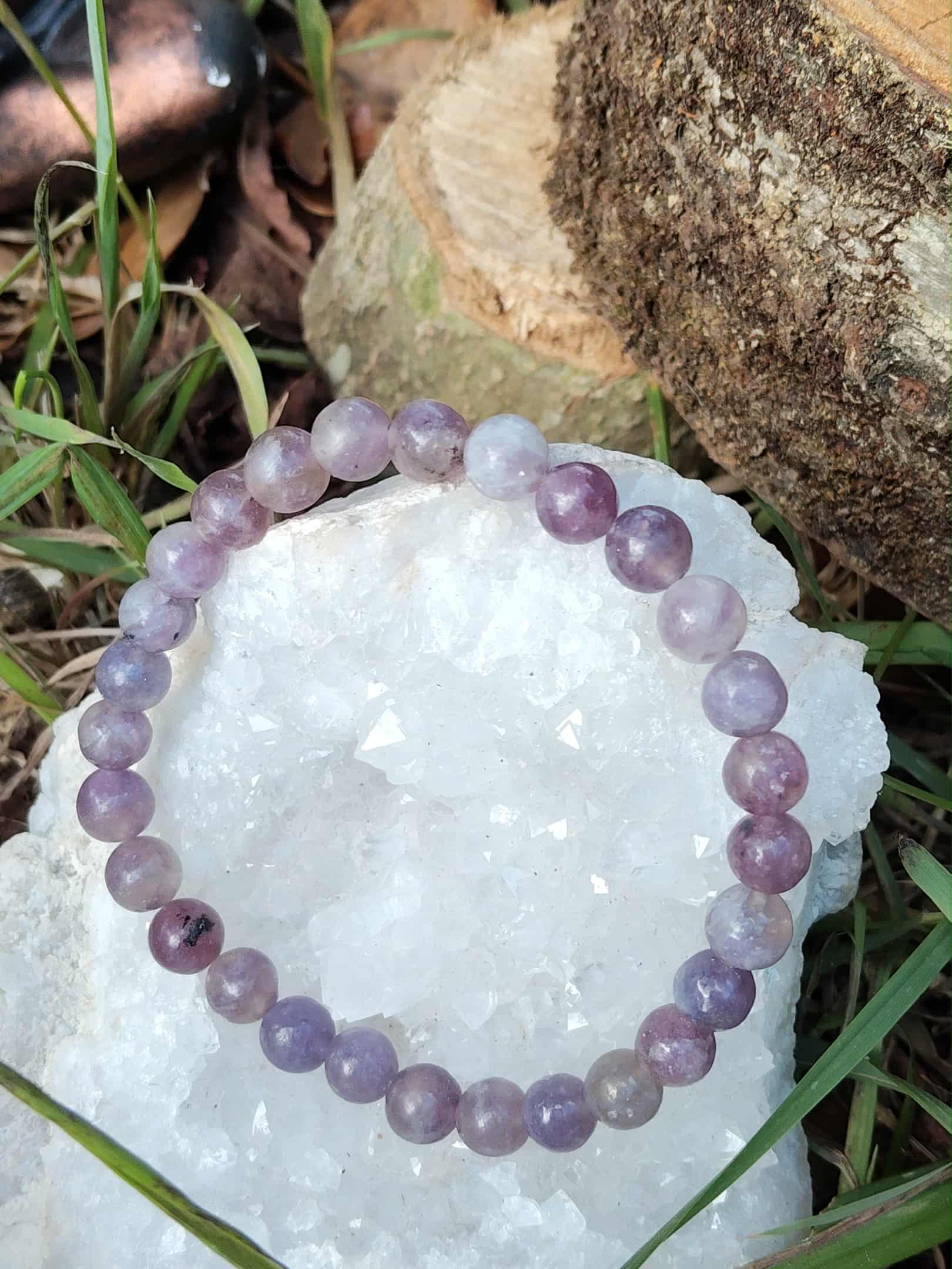 Bracelet tourmaline rose sur eudialyte posé sur géode de quartz avec décor végétal, harmonie du cœur et apaisement profond