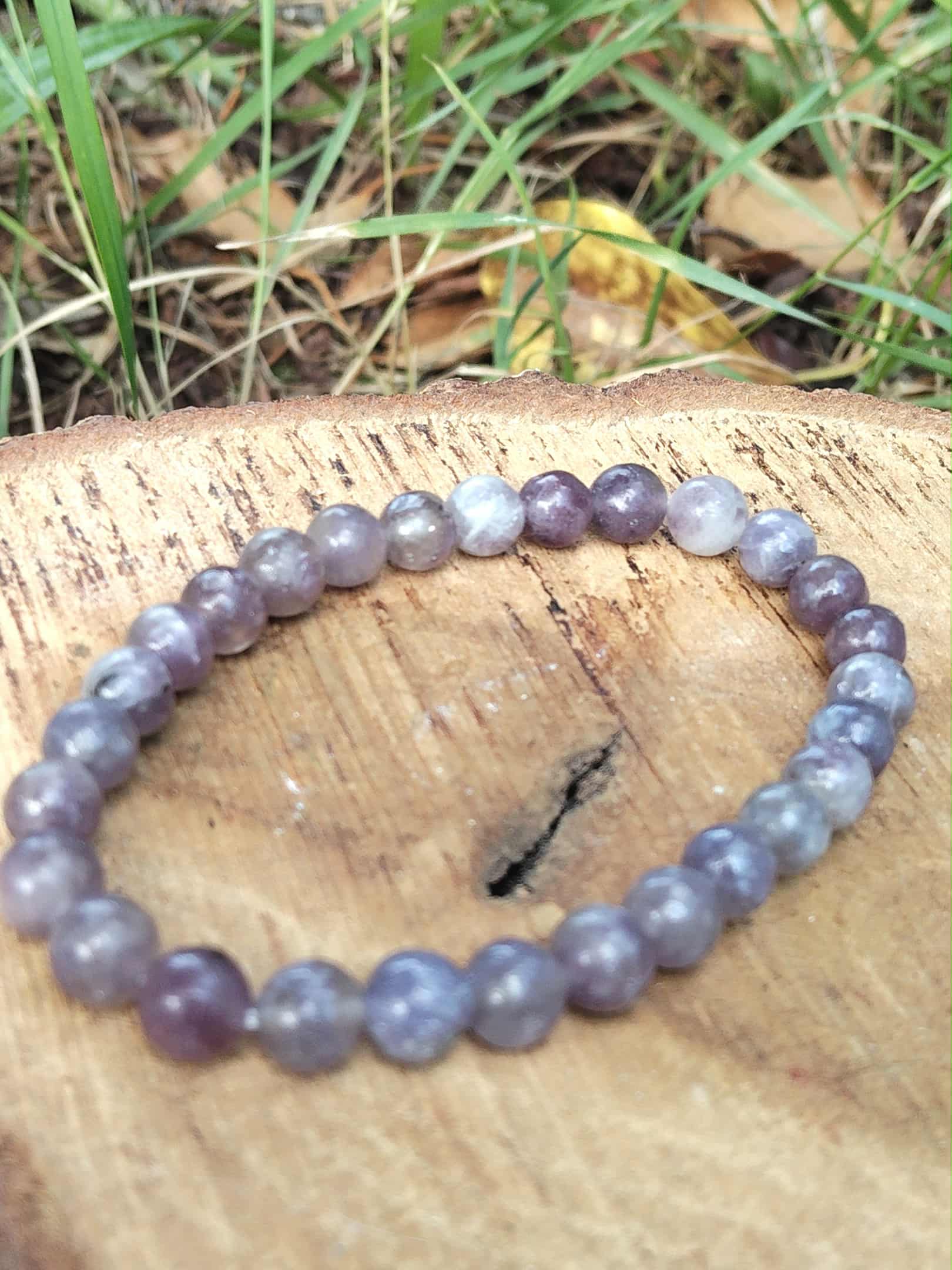 Bracelet tourmaline rose sur eudialyte sur tranche de bois avec fond végétal, écoute intérieure et tendresse émotionnelle