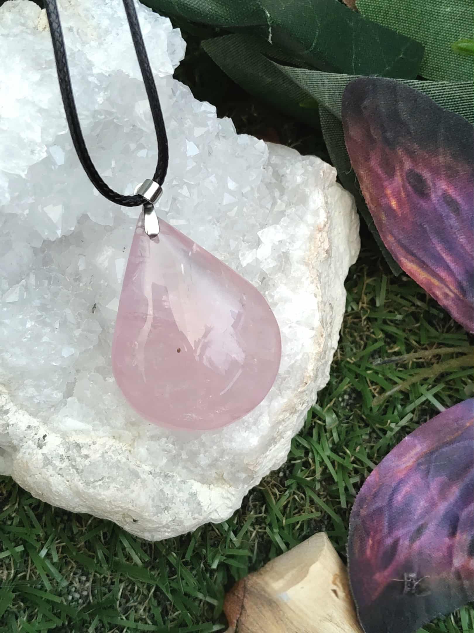 Quartz rose pendentif – vibrations douces, lâcher-prise sur géode de quartz posé sur  décor végétal