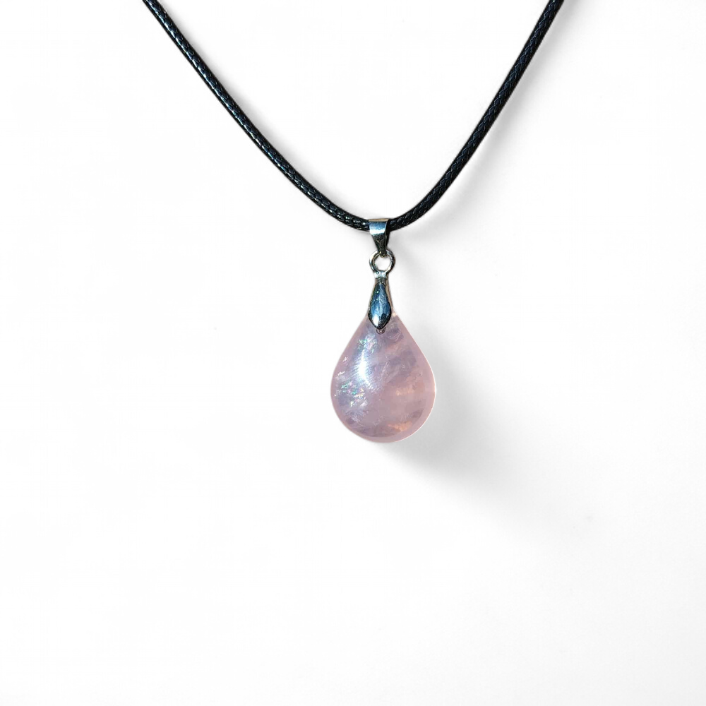 Pendentif goutte en quartz rose sur fond blanc, collier en pierre naturelle relié à l’amour de soi, à la douceur émotionnelle et au réconfort intérieur.