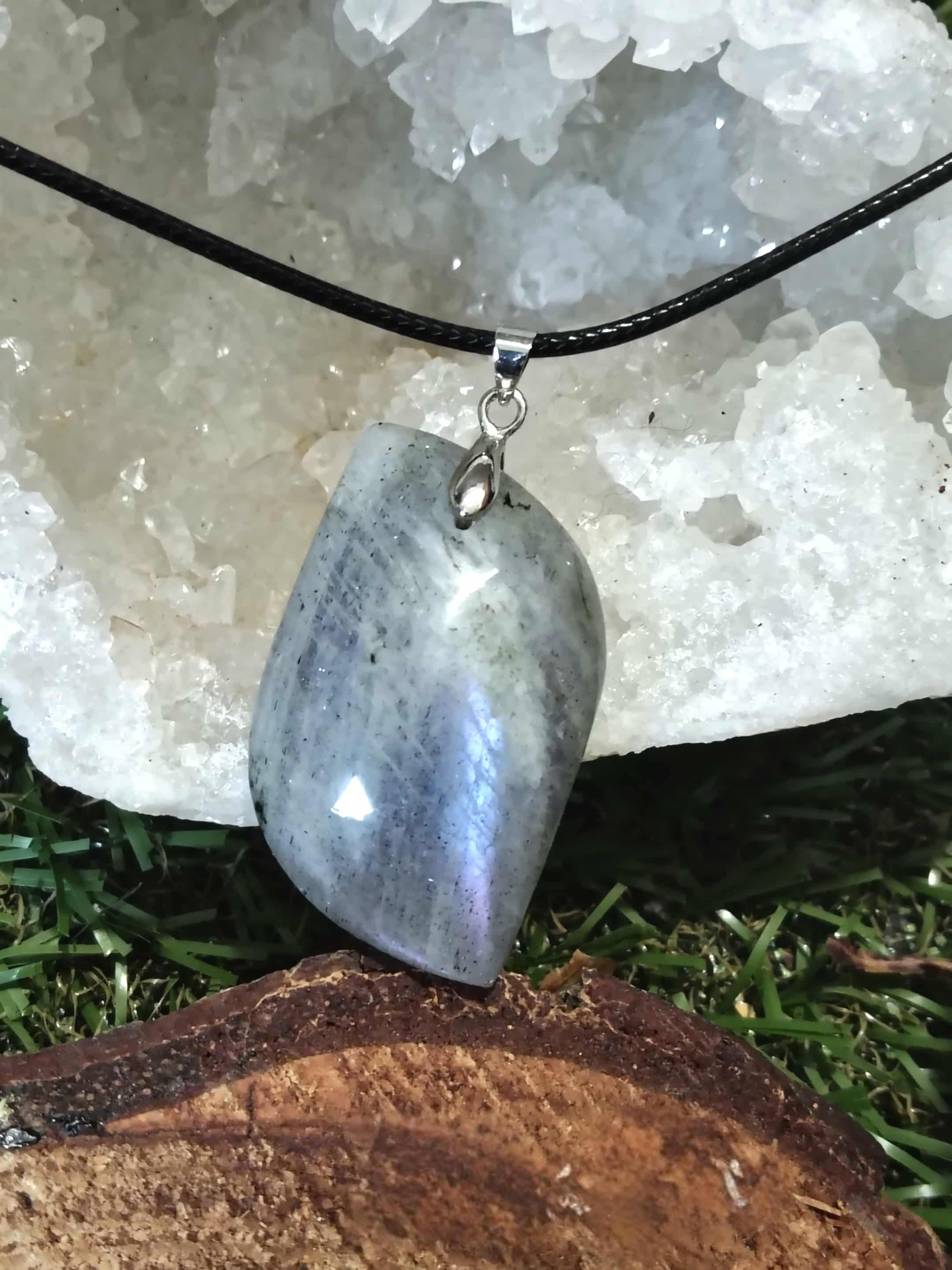 Pendentif labradorite arc-en-ciel devant druse de quartz, posé sur rondin, collier en pierre naturelle évoquant le discernement, la vigilance intérieure et la paix du mental.