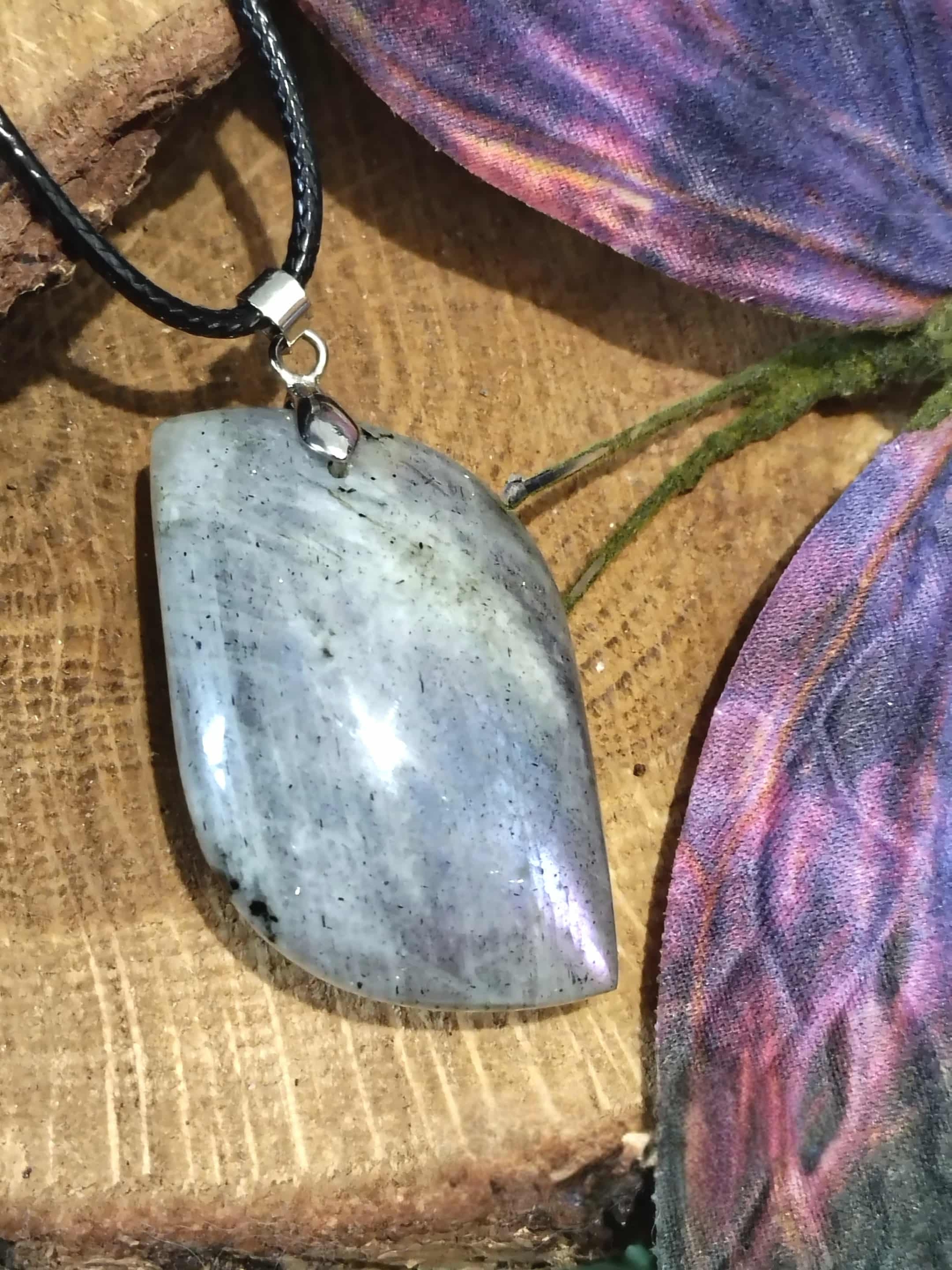 Pendentif labradorite avec bélière en acier inoxydable sur fond bois, pierre naturelle associée à la stabilité émotionnelle, au recentrage et à la présence à soi.
