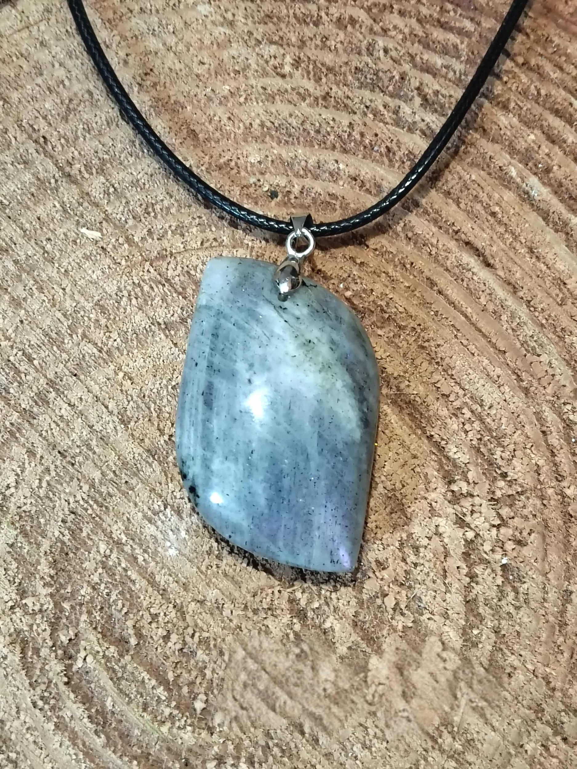 Pendentif labradorite arc-en-ciel sur rondin de bois, pierre naturelle associée à la lucidité, à la protection subtile et à la clarté d’esprit.