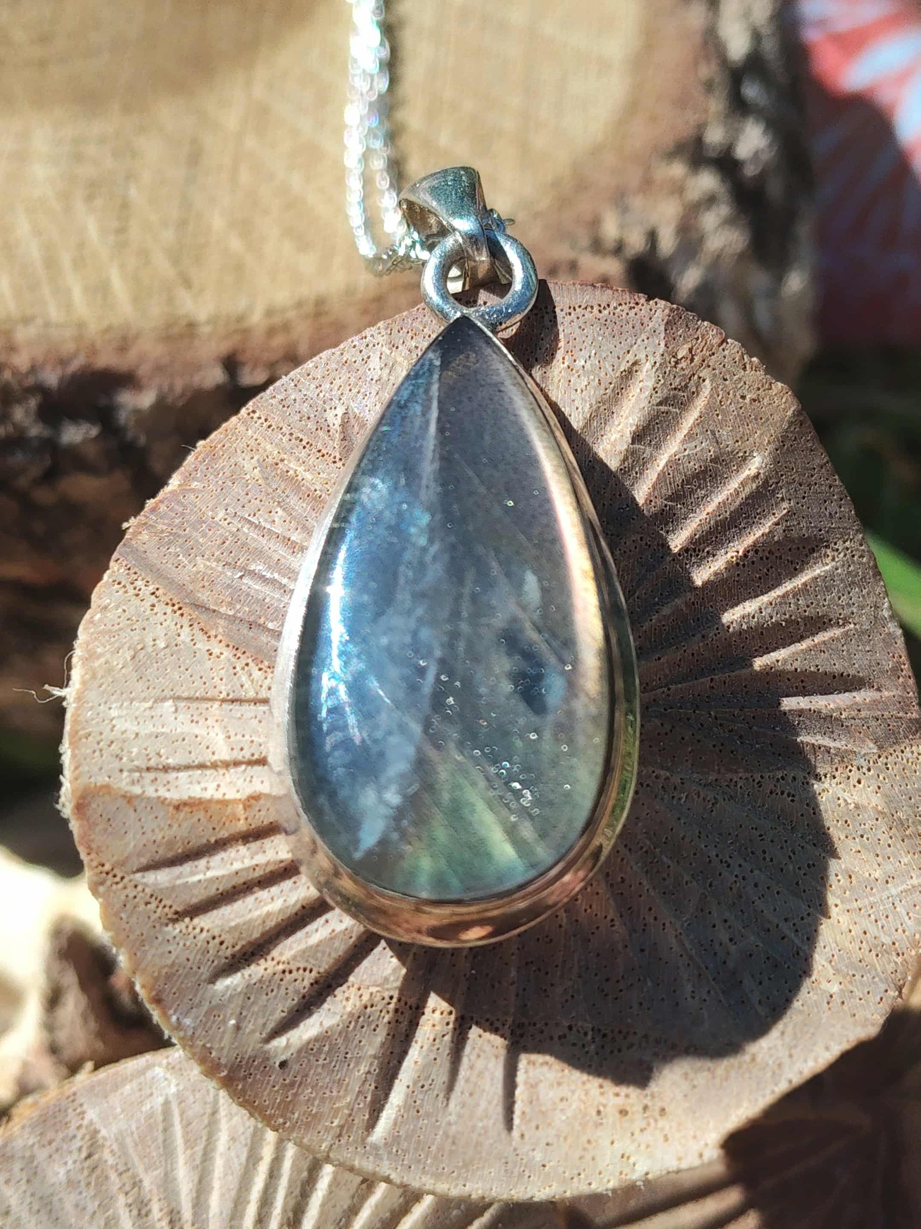 Pendentif labradorite violette en goutte avec argent 925 sur décor bois sculpté, bijou naturel relié à l’intuition, à la confiance calme et à la profondeur intérieure.