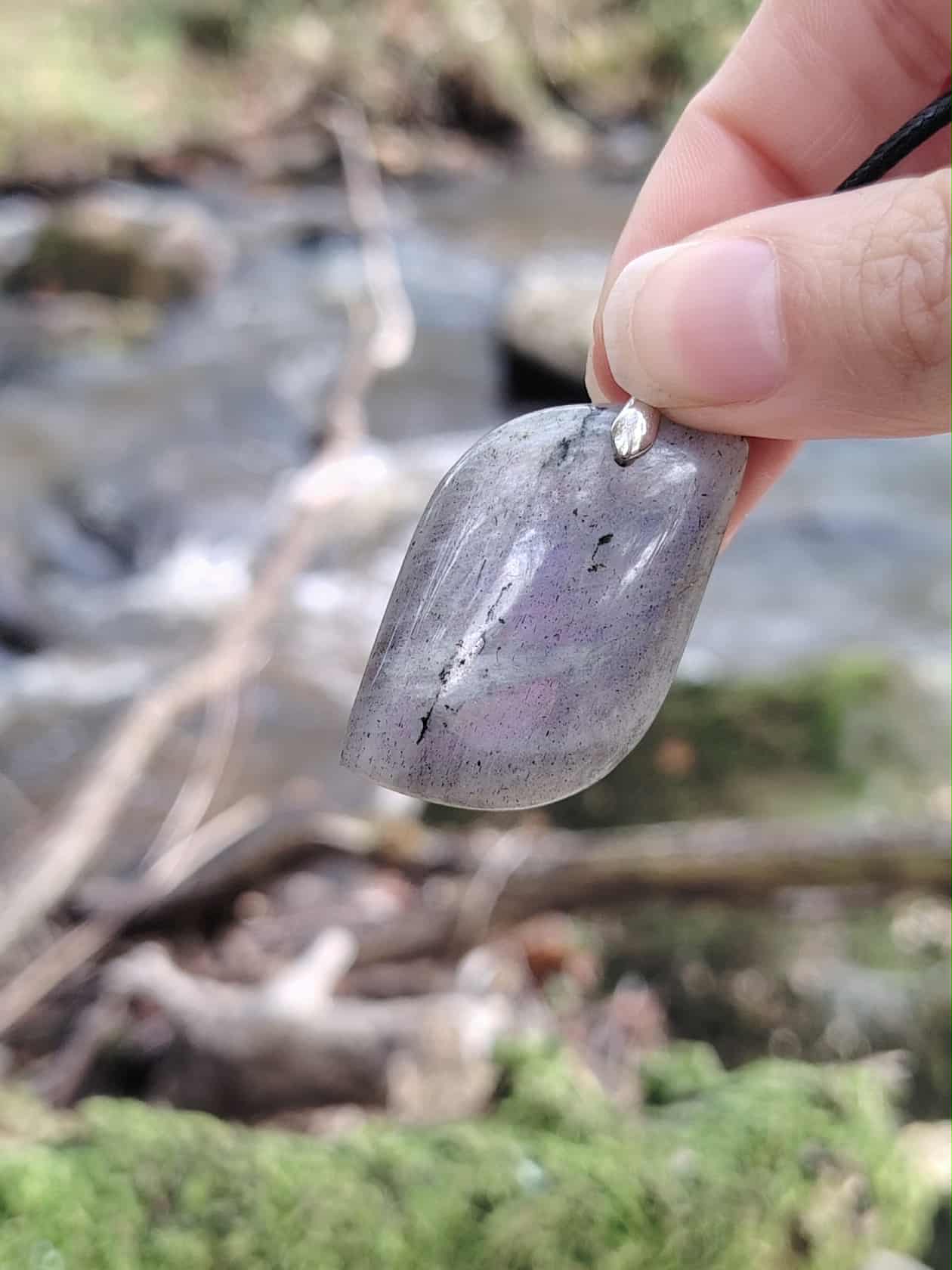 Bijou en labradorite grise près d’un cours d’eau, pierre naturelle évoquant l’intuition, la fluidité intérieure et l’équilibre émotionnel.