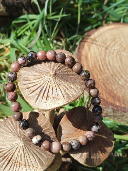 Bracelet rhodonite 6 mm sur champignons décoratifs dans l’herbe, sérénité relationnelle, chaleur du cœur et réassurance émotionnelle