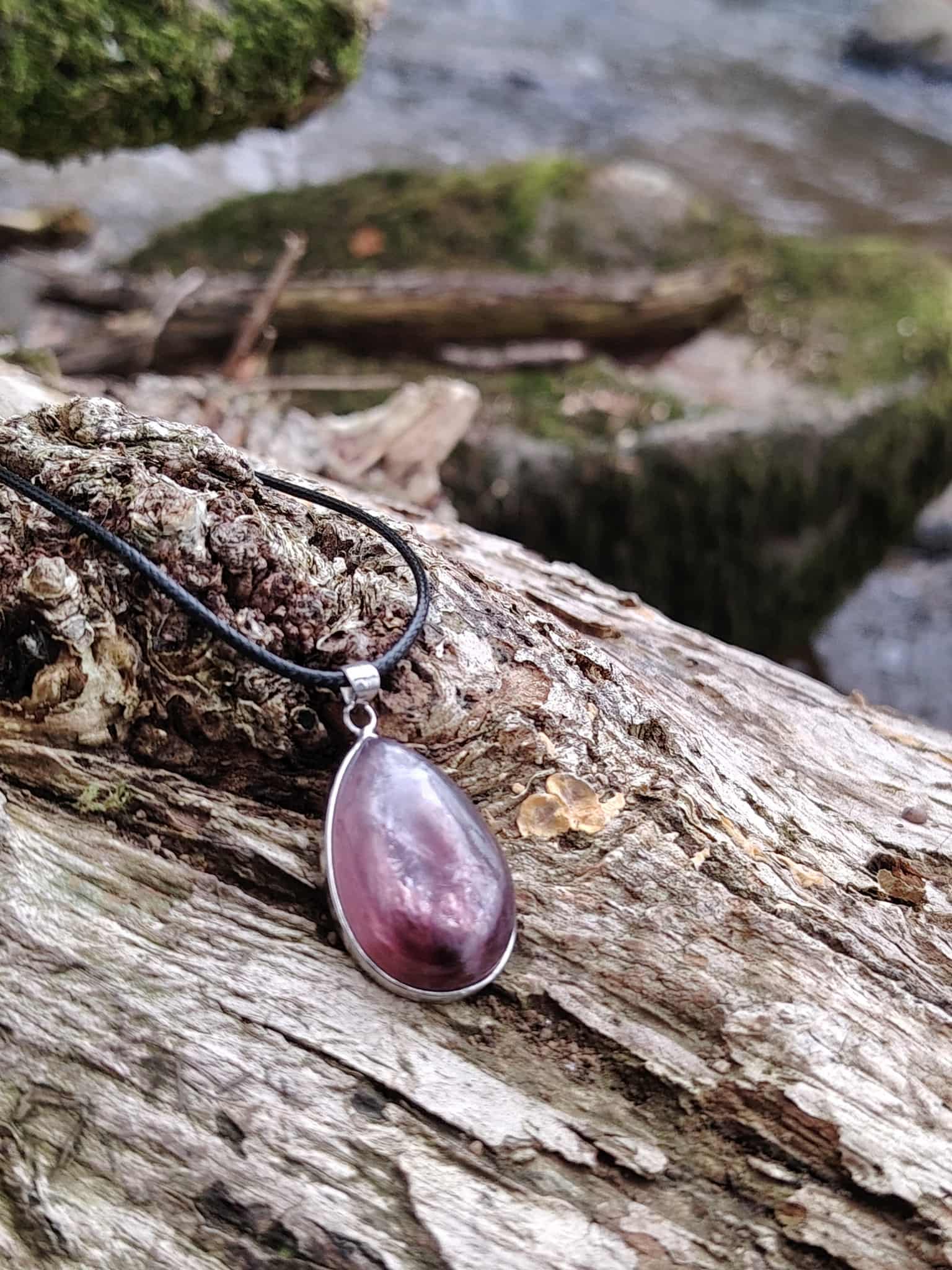 Pendentif lépidolite en argent 925 sur bois flotté au bord de l’eau, bijou en pierre naturelle relié à l’apaisement, à la douceur du cœur et à l’équilibre émotionnel.