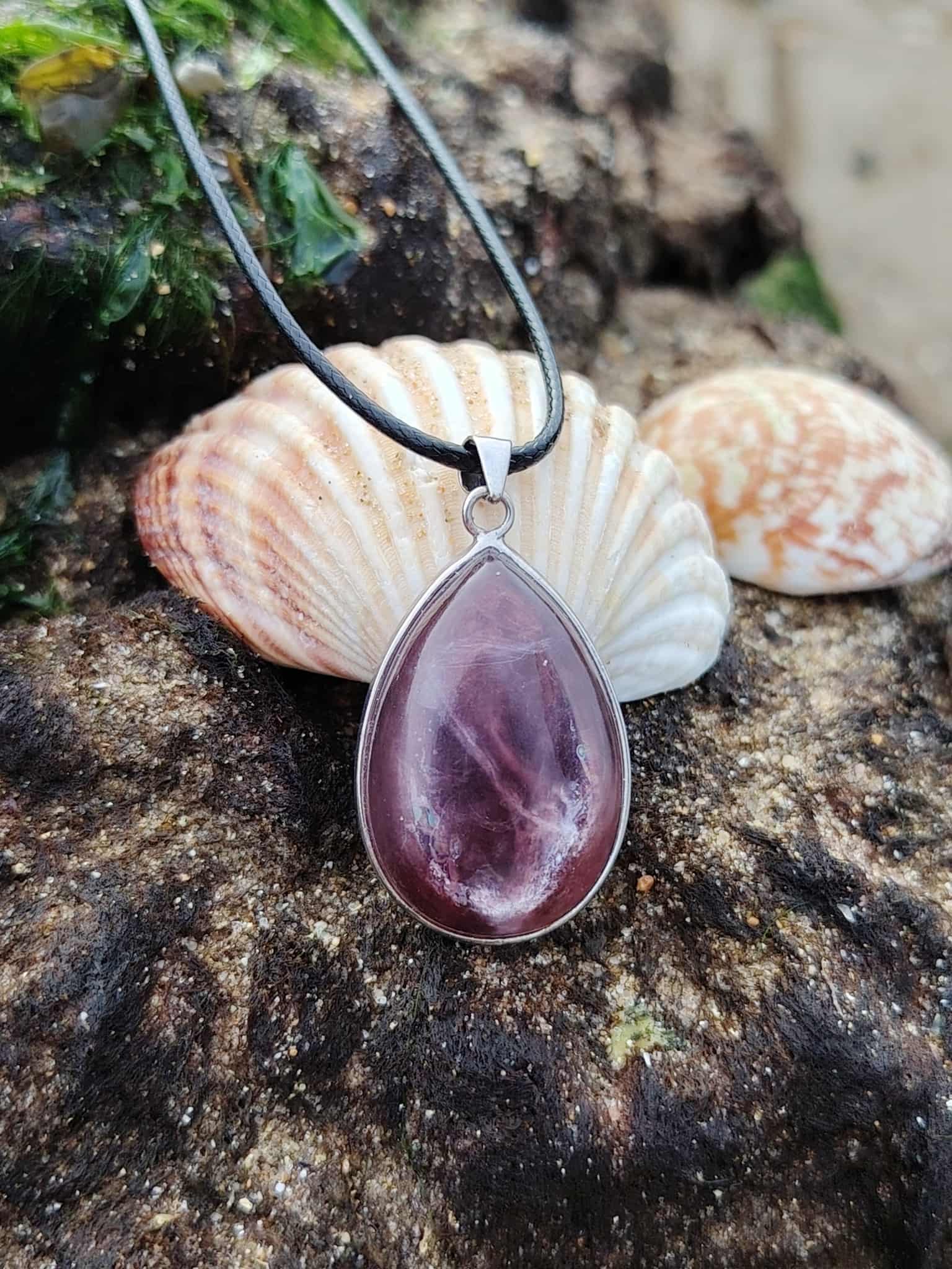 Pendentif lépidolite en argent 925 posé sur décor naturel avec coquillages, bijou en pierre naturelle associé à l’apaisement, à l’équilibre intérieur et à la douceur émotionnelle.