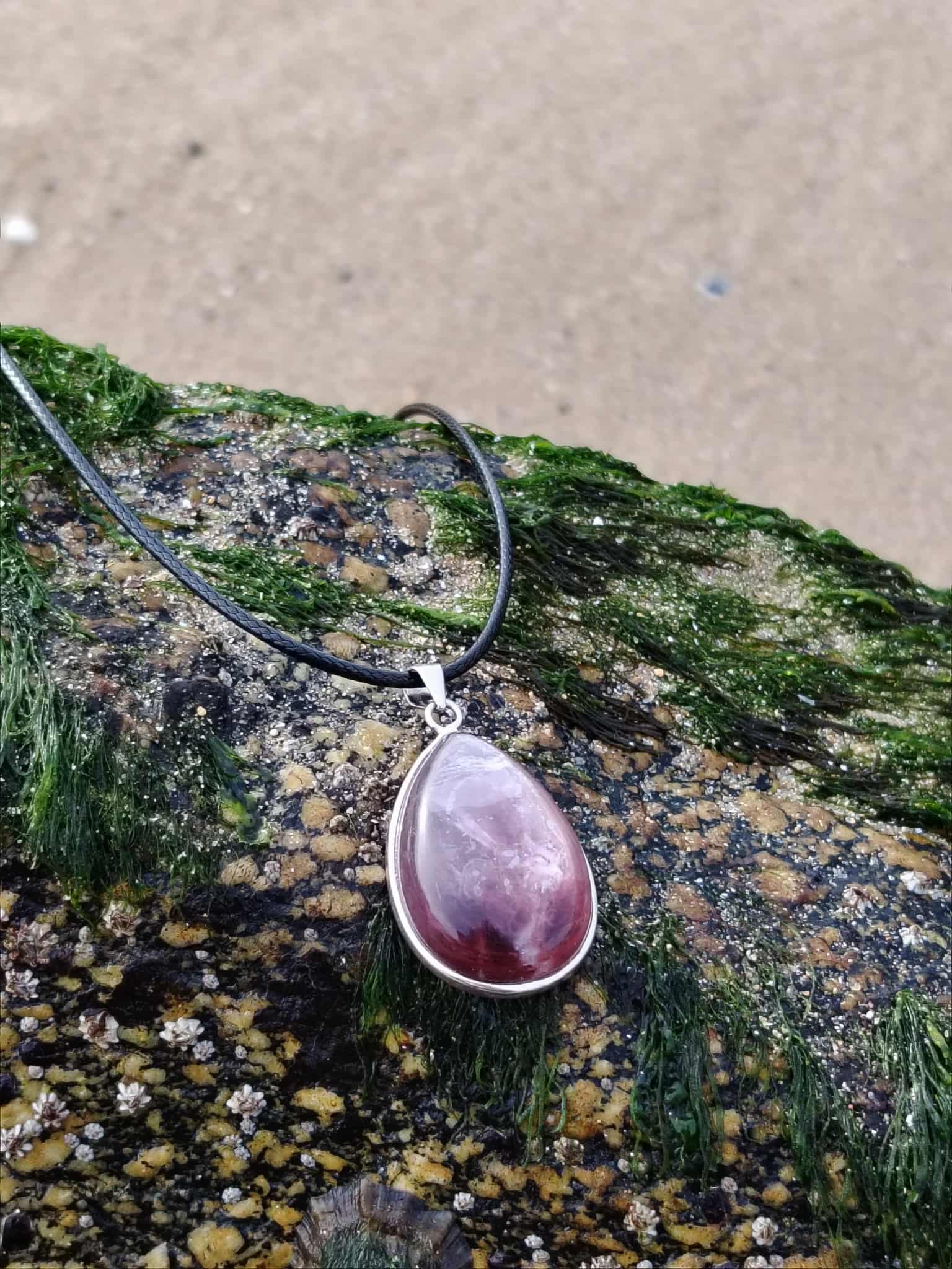 Pendentif lépidolite en argent 925 posé sur bois flotté en bord de mer, bijou en pierre naturelle associé à la sérénité, au lâcher-prise et à l’harmonie émotionnelle.