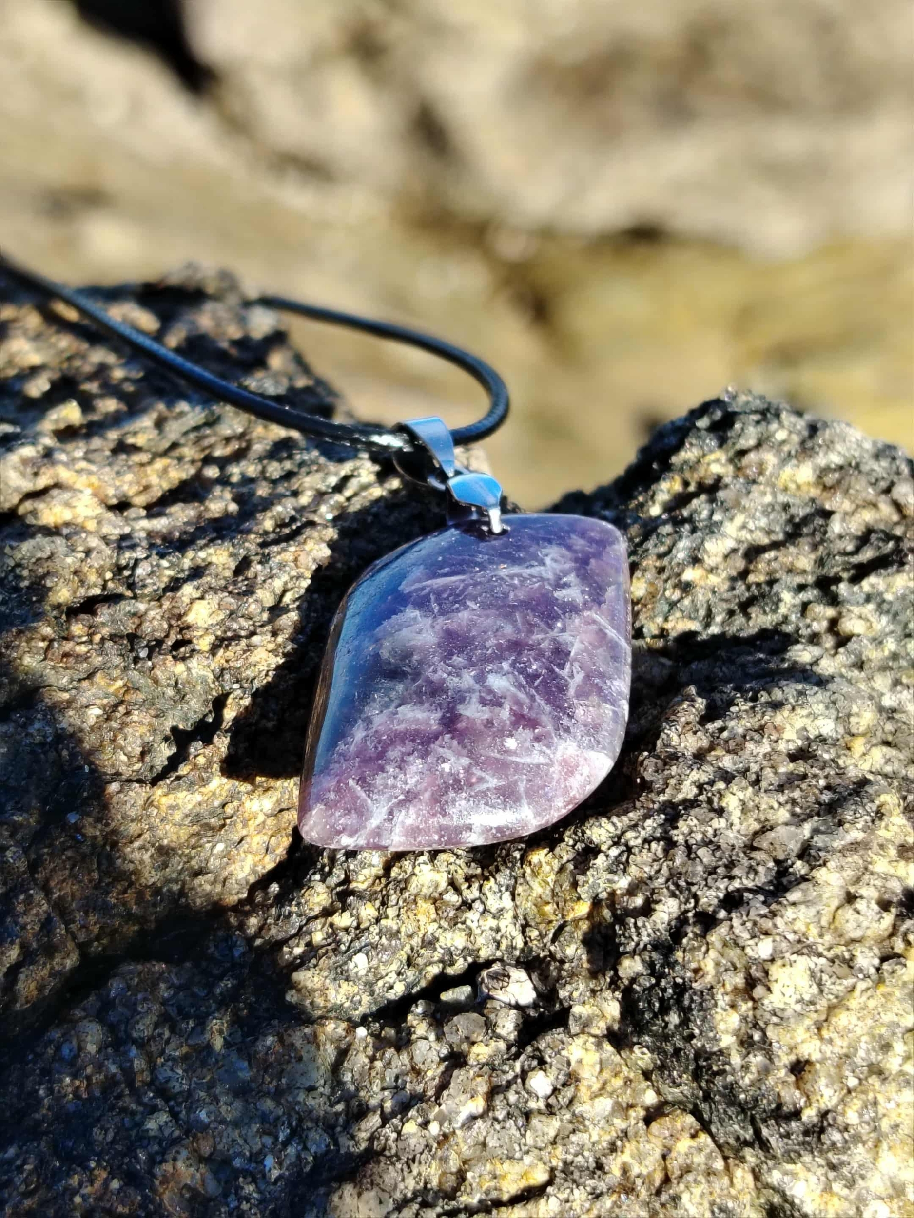 Pendentif lépidolite rectangulaire sur rocher en Bretagne, bijou en pierre naturelle évoquant la confiance douce, la stabilité émotionnelle et le réconfort intérieur.