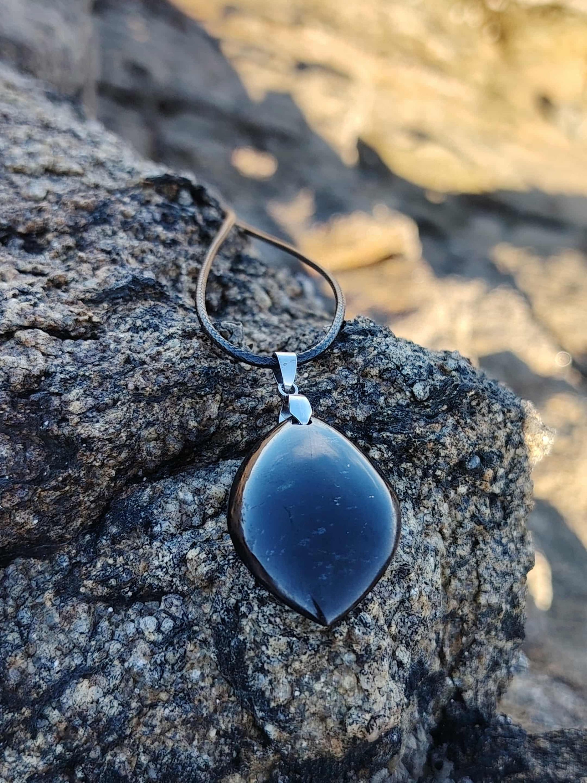 Pendentif tourmaline noire marquise posé sur rocher en bord de mer en Bretagne, bijou en pierre naturelle associé à la protection, à l’ancrage et à la stabilité intérieure.