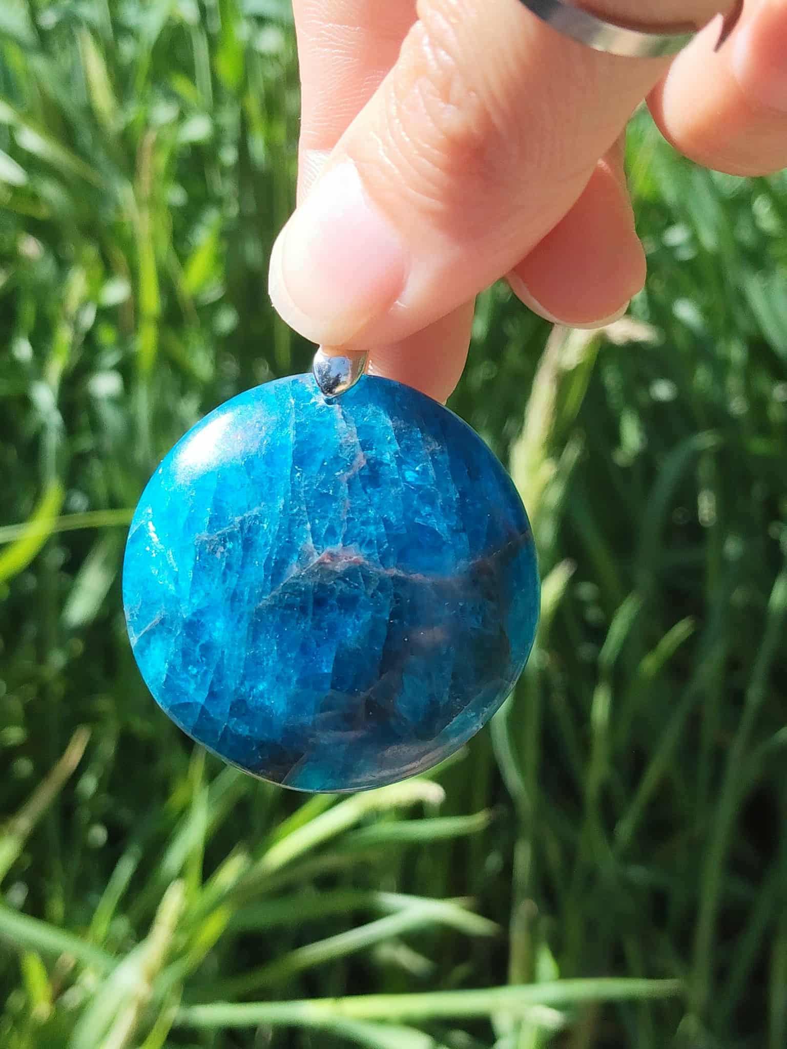 Pendentif apatite bleue qualité extra tenu à la main, pierre naturelle reliée à la clarté d’expression, à l’équilibre intérieur et à la confiance paisible.