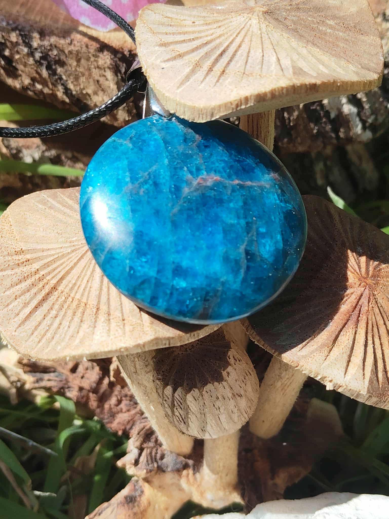 Pendentif apatite bleue sur champignon beige en décor nature, pierre naturelle évoquant la douceur émotionnelle, l’intuition sensible et le recentrage.