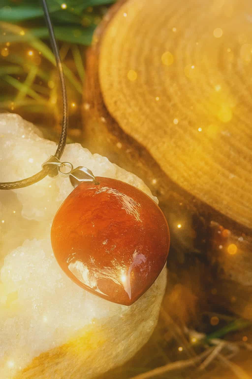 Pendentif pierre jaspe rouge sur amas de quartz et rondin de bois, bijou en pierre naturelle évoquant le recentrage, la solidité émotionnelle et la présence à soi.