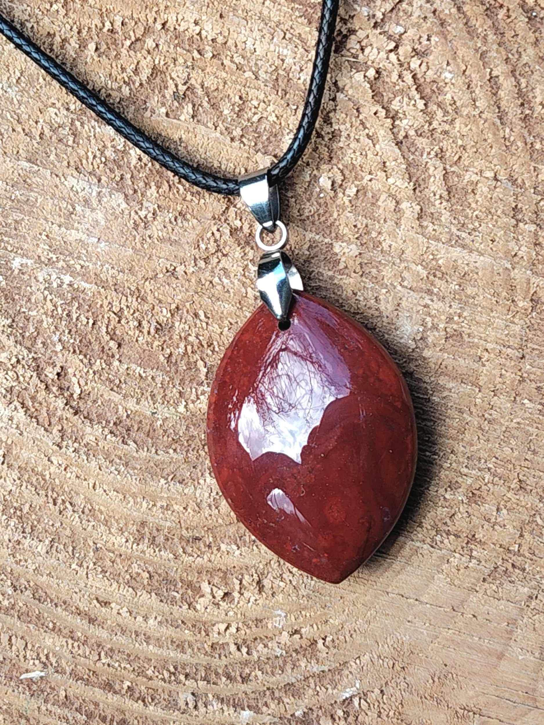 Pendentif jaspe rouge sur rondin de bois, pierre naturelle reliée à l’enracinement, à la volonté et à l’équilibre intérieur.
