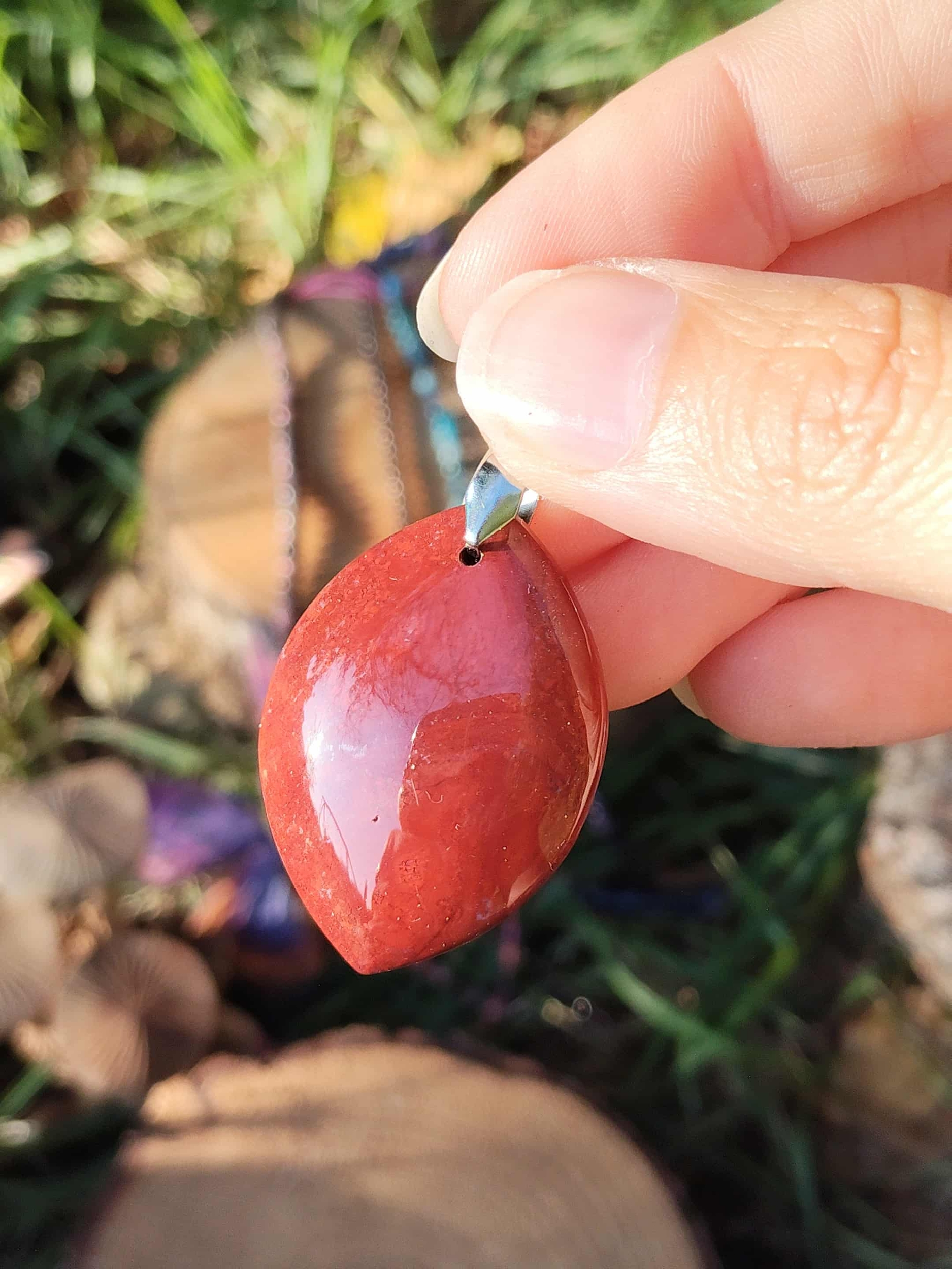 Bijou jaspe rouge poli tenu dans la main, pierre naturelle associée au courage, à l’endurance intérieure et à la confiance posée.