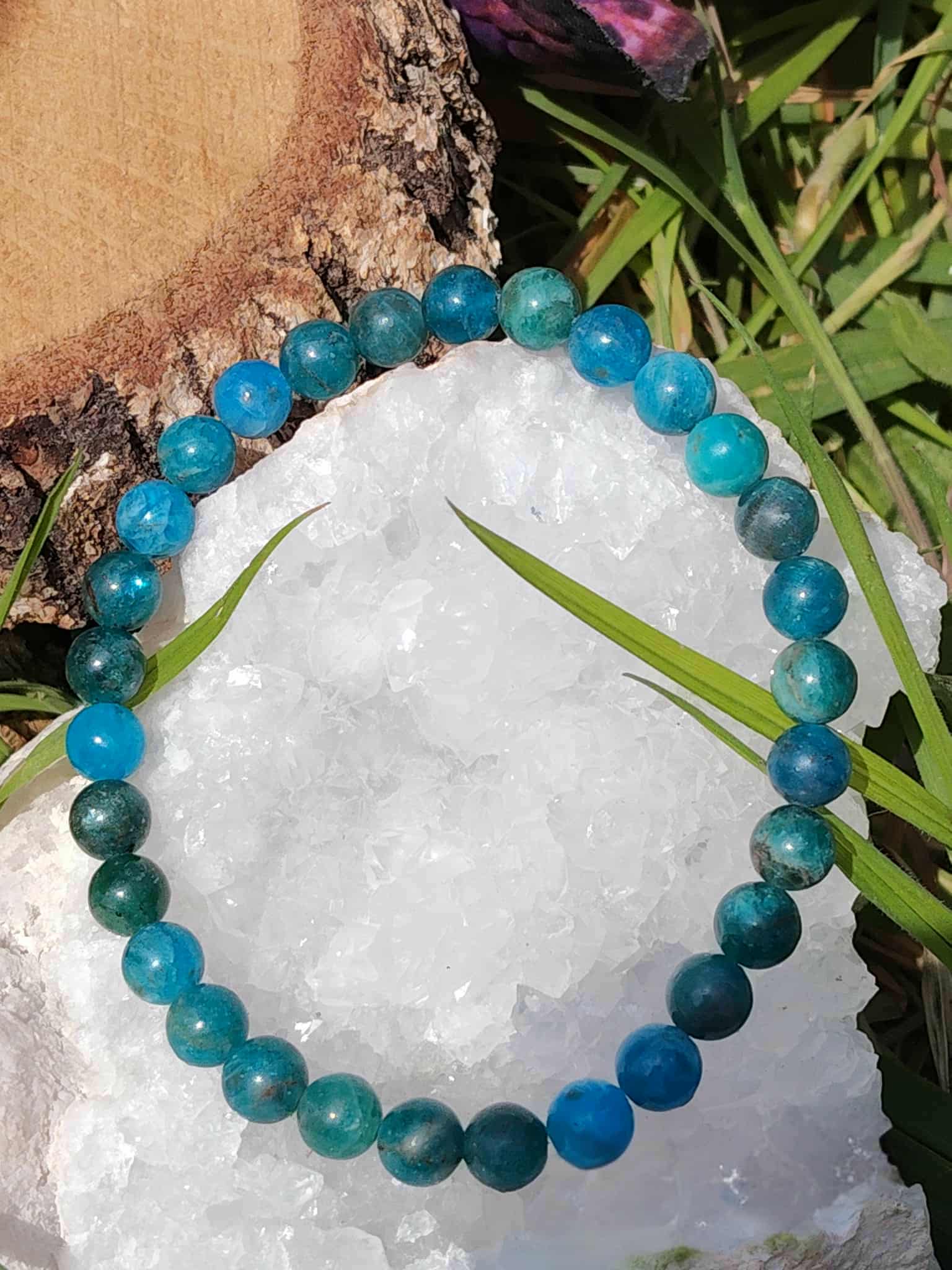 Bracelet en apatite bleue posé sur amas de quartz avec herbe, bijou lithothérapie pour relâcher la pression mentale et adoucir les émotions