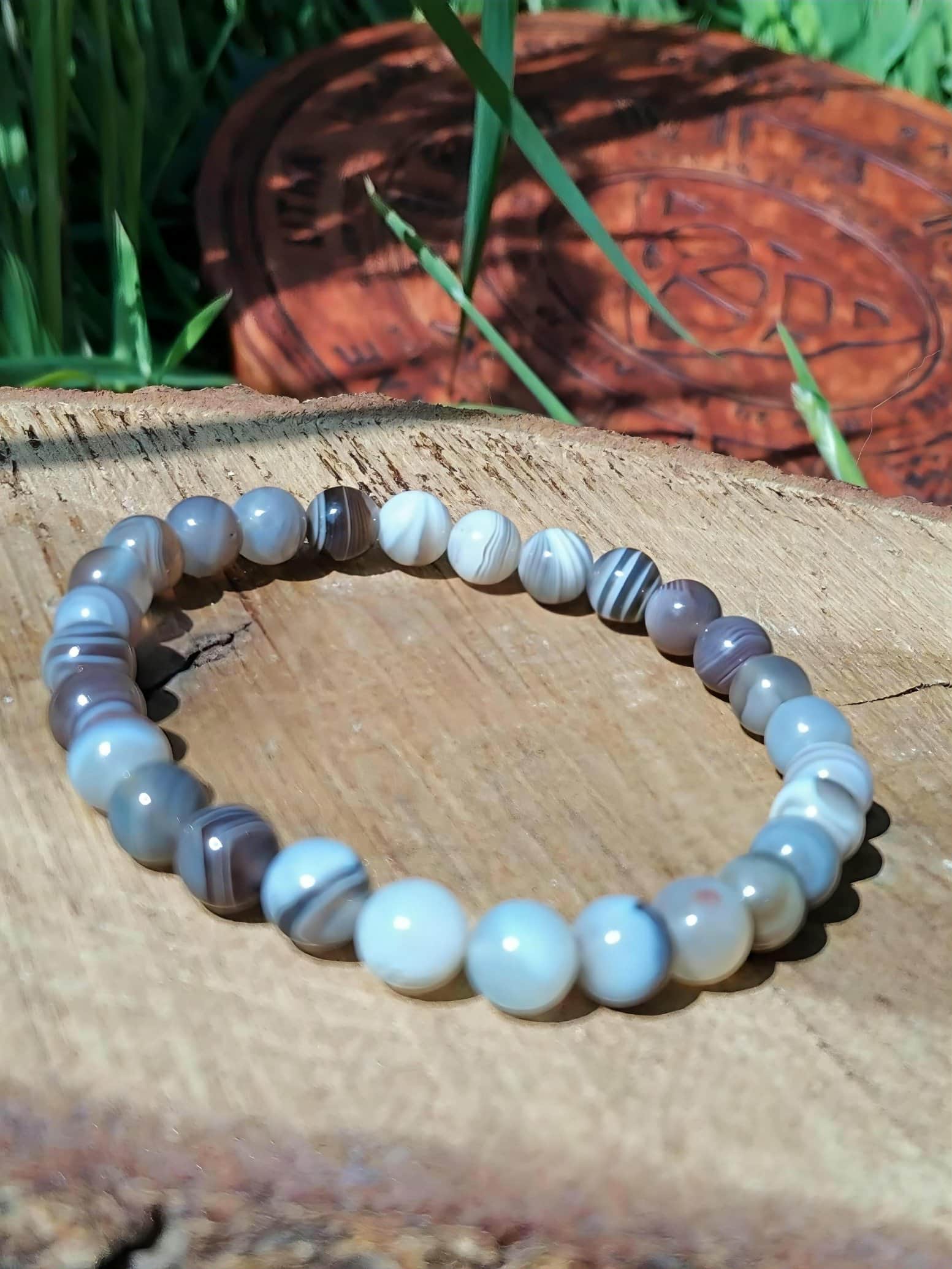 Bracelet Agate du Botswana 6 mm posé sur roche, perles naturelles en décor minéral, calme intérieur et stabilité émotionnelle
