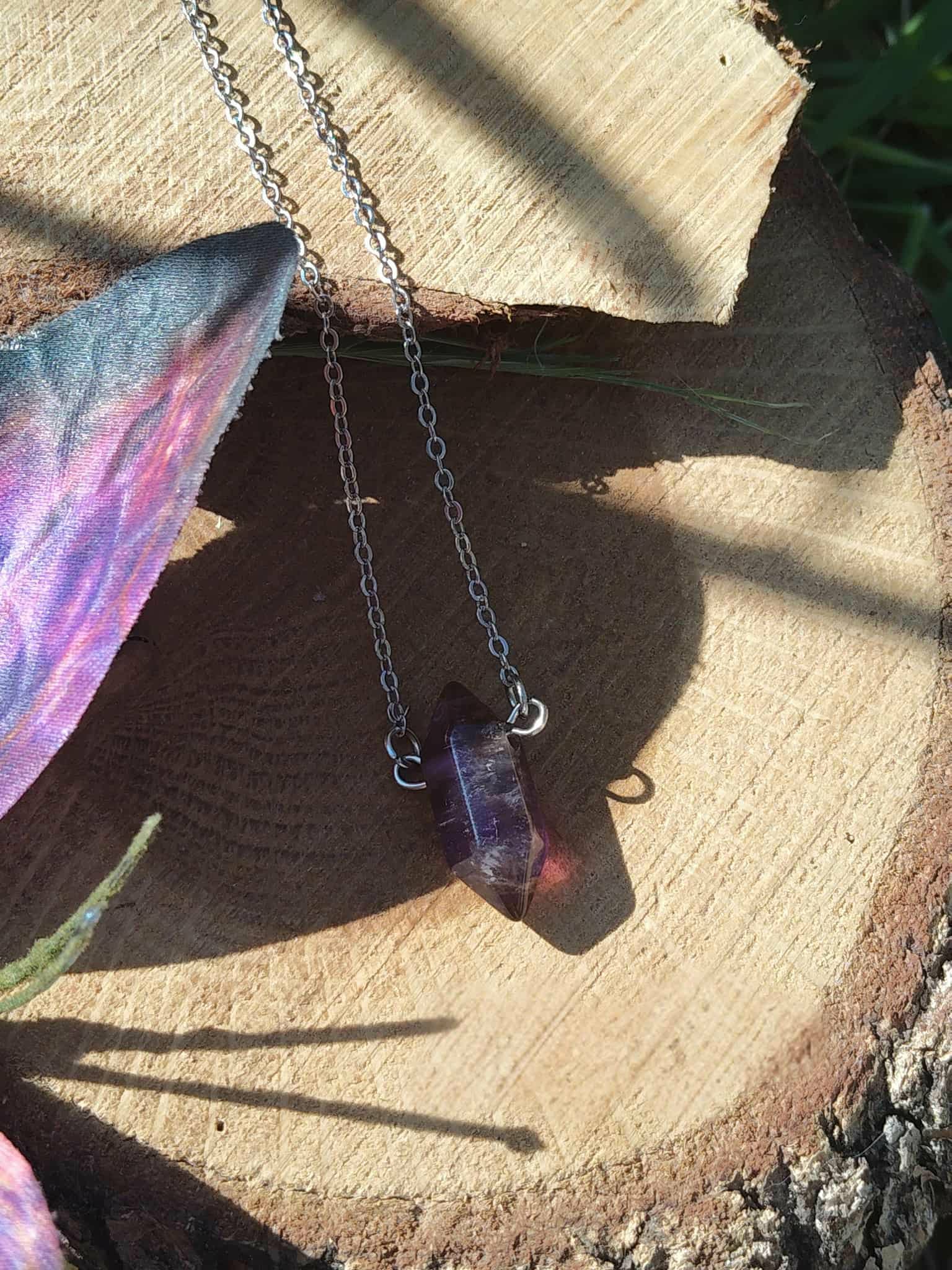 Pendentif améthyste en pointe sur chaîne fine, photo sur tranche de bois avec décor féerique, bijou lithothérapie évoquant la douceur du cœur, le lâcher-prise et la sagesse intérieure.