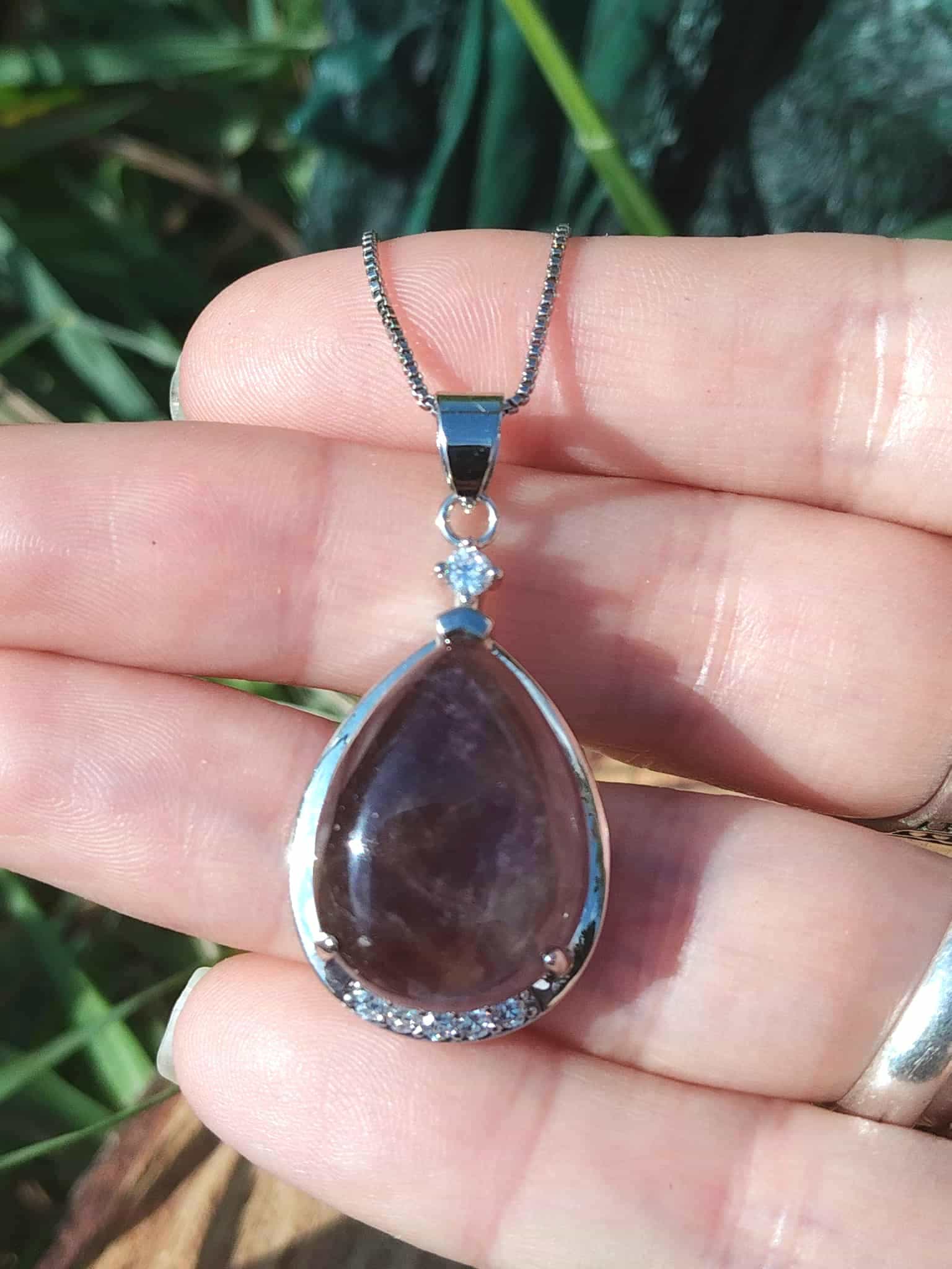 Pendentif goutte améthyste tenu dans la main, pierre naturelle violette pour calme intérieur et énergie sereine