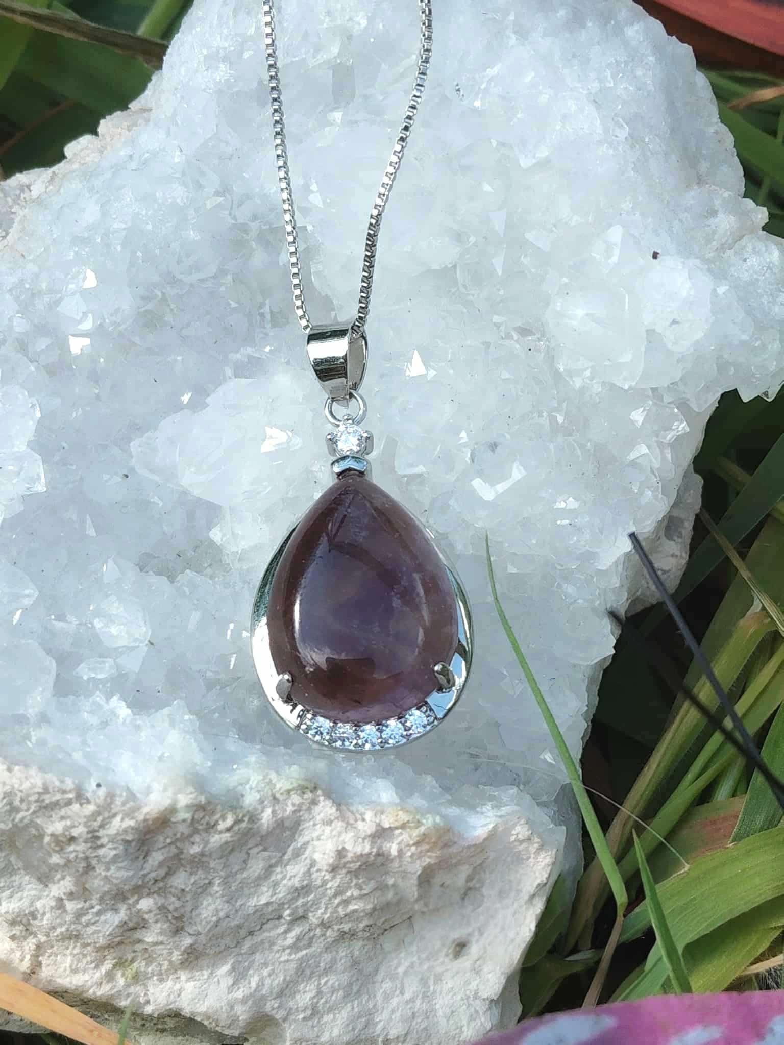 Pendentif goutte améthyste monté sur métal argenté, posé sur amas de quartz blanc en extérieur, paix intérieure et élévation douce