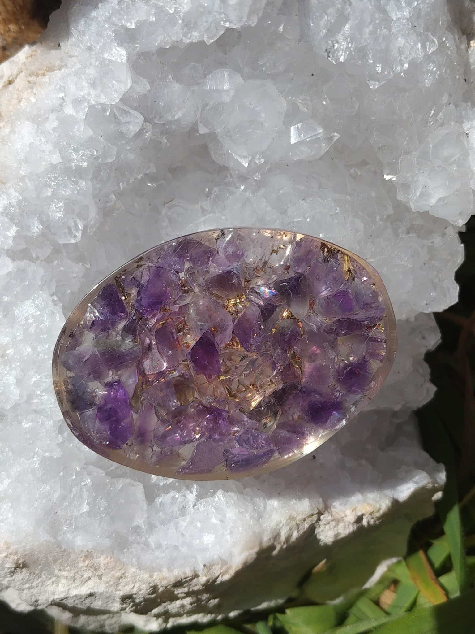 Petit galet en orgonite améthyste posé sur une grande géode de cristal blanc en extérieur, création énergétique pour soutenir le bien-être mental, émotionnel et spirituel et sublimer une décoration ésotérique