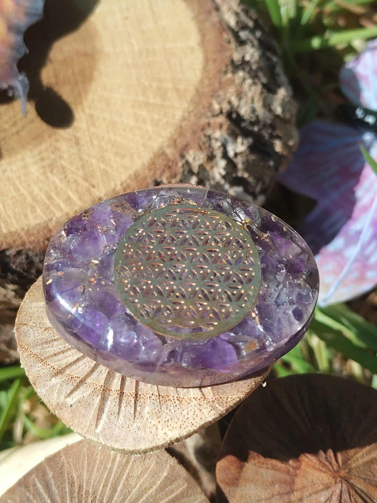 Petit galet orgonite améthyste fleur de vie, mis en scène sur des supports en bois, accessoire zen pour créer une atmosphère douce, favoriser la relaxation et accompagner le travail énergétique