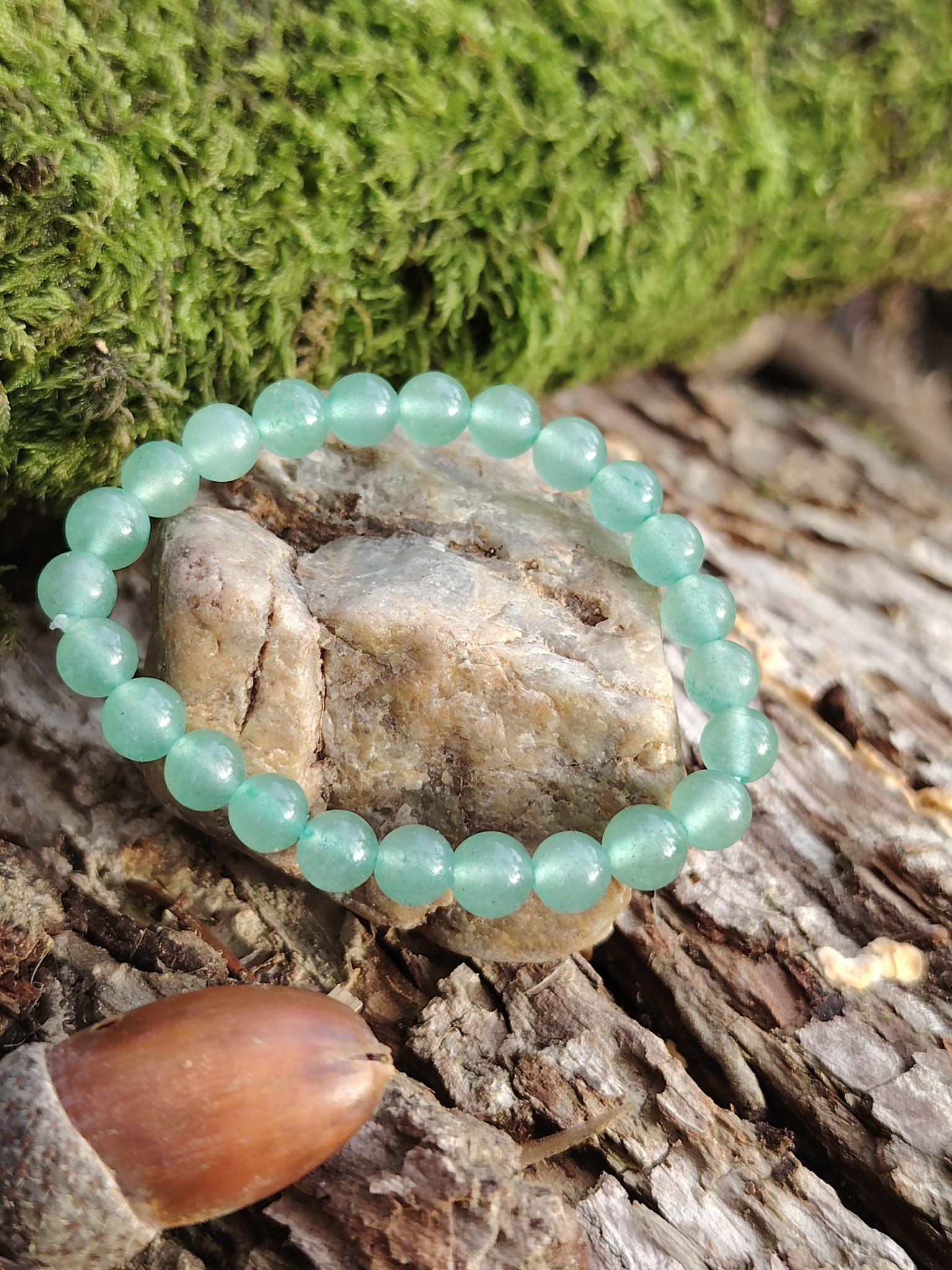 Bracelet aventurine verte 6 mm sur écorce avec mousse, photo nature en Bretagne, douceur émotionnelle et respiration du cœur.