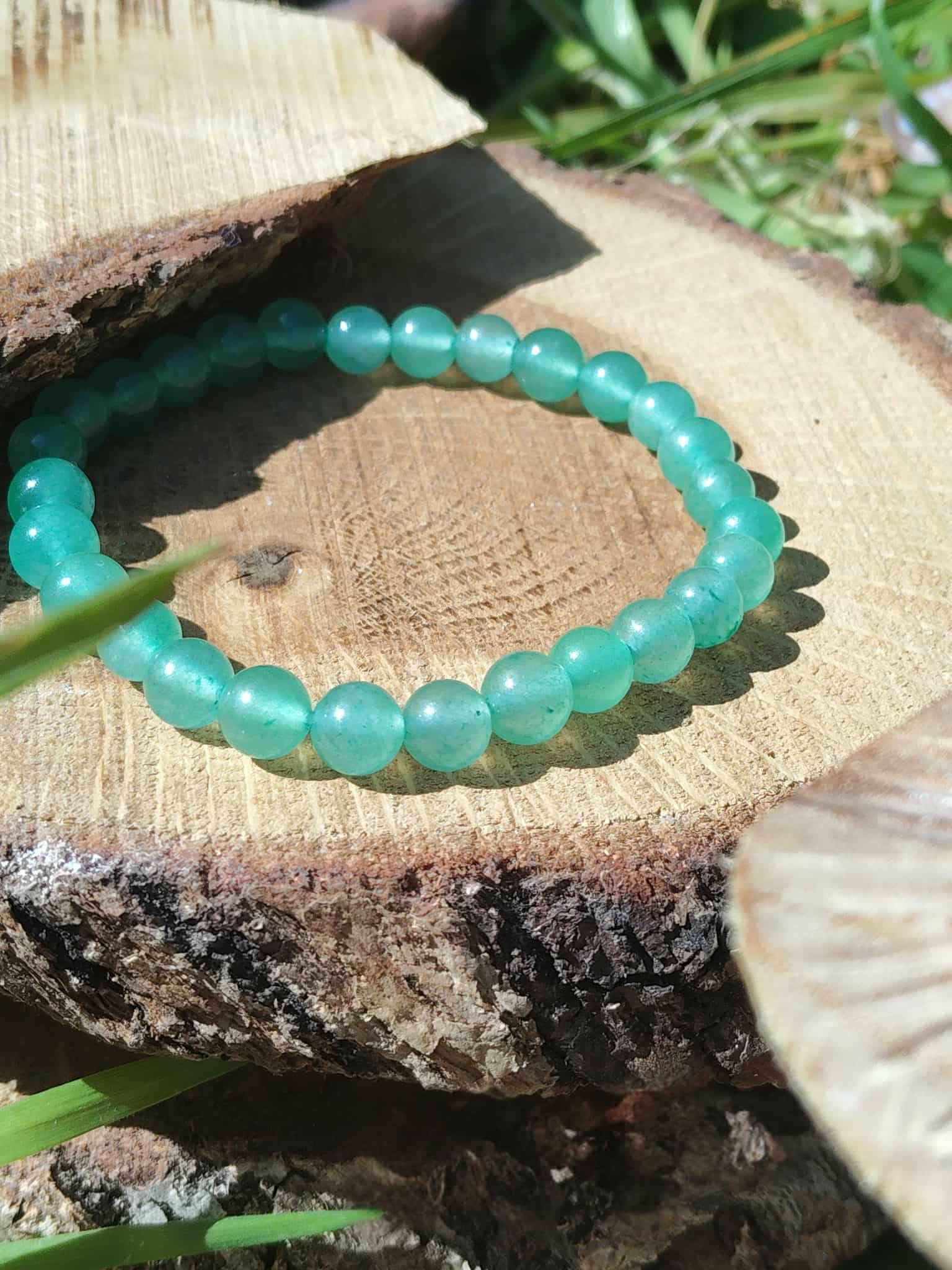 Bracelet aventurine verte 6 mm sur souche d’arbre au jardin, pierre naturelle pour sérénité, réconfort et stabilité du ressenti.