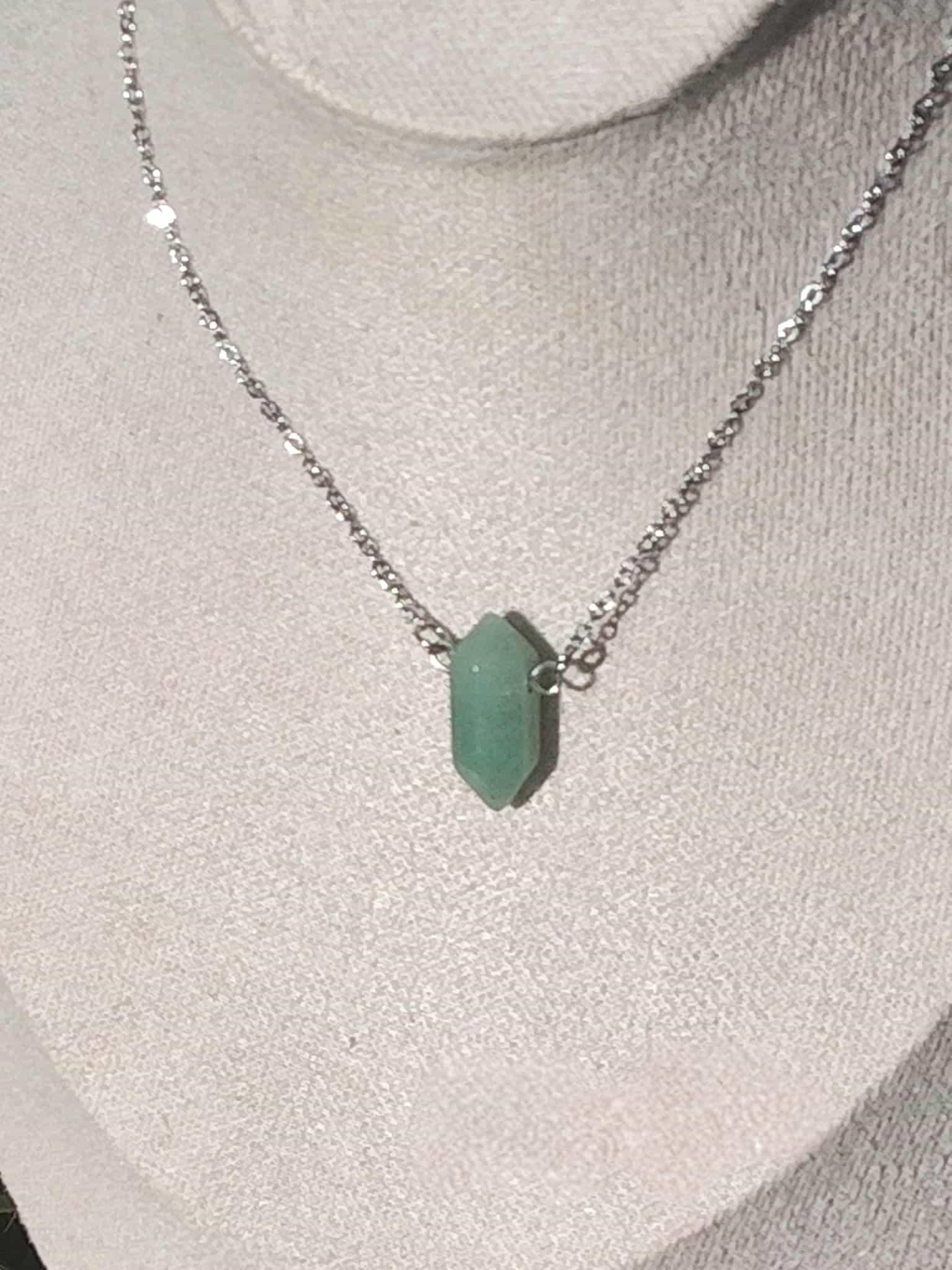 Collier pendentif pointe aventurine verte sur buste blanc avec chaîne fine en acier inoxydable, bijou pierre naturelle évoquant la paix mentale, la stabilité affective et l’harmonie intérieure.