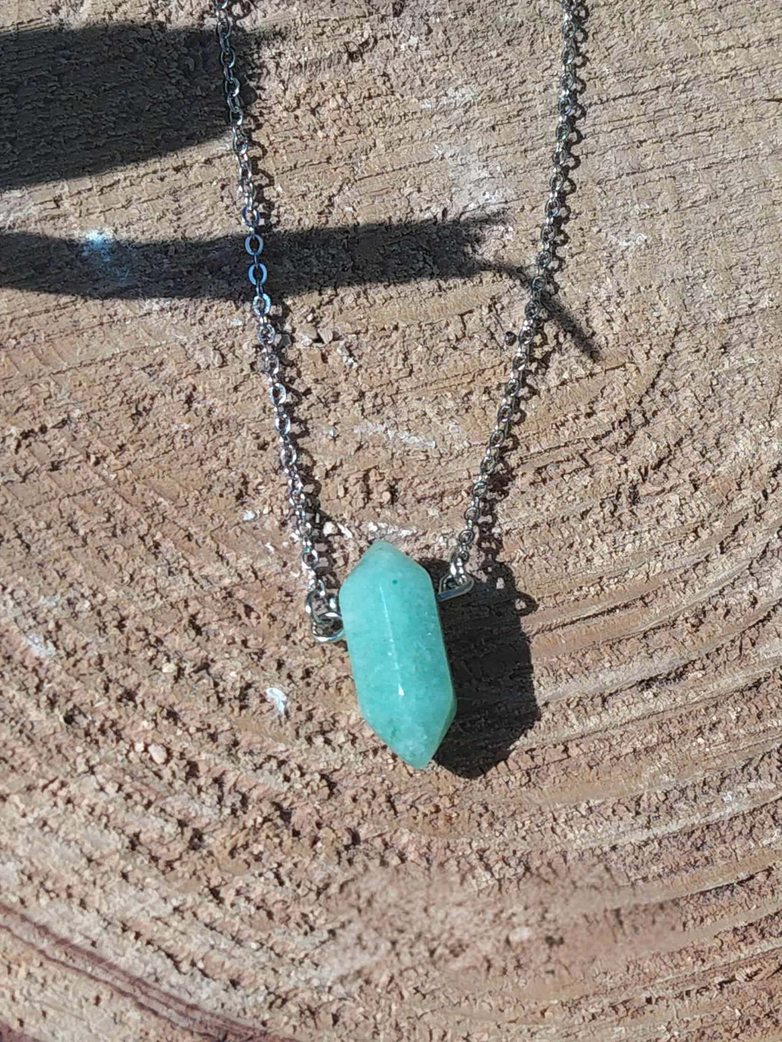 Collier avec pendentif en pointe d’aventurine verte, chaîne métallique posée sur une tranche de bois – bijou Magic Gaïa en pierre naturelle, lithothérapie pour soutien du chakra du cœur et du bien-être émotionnel