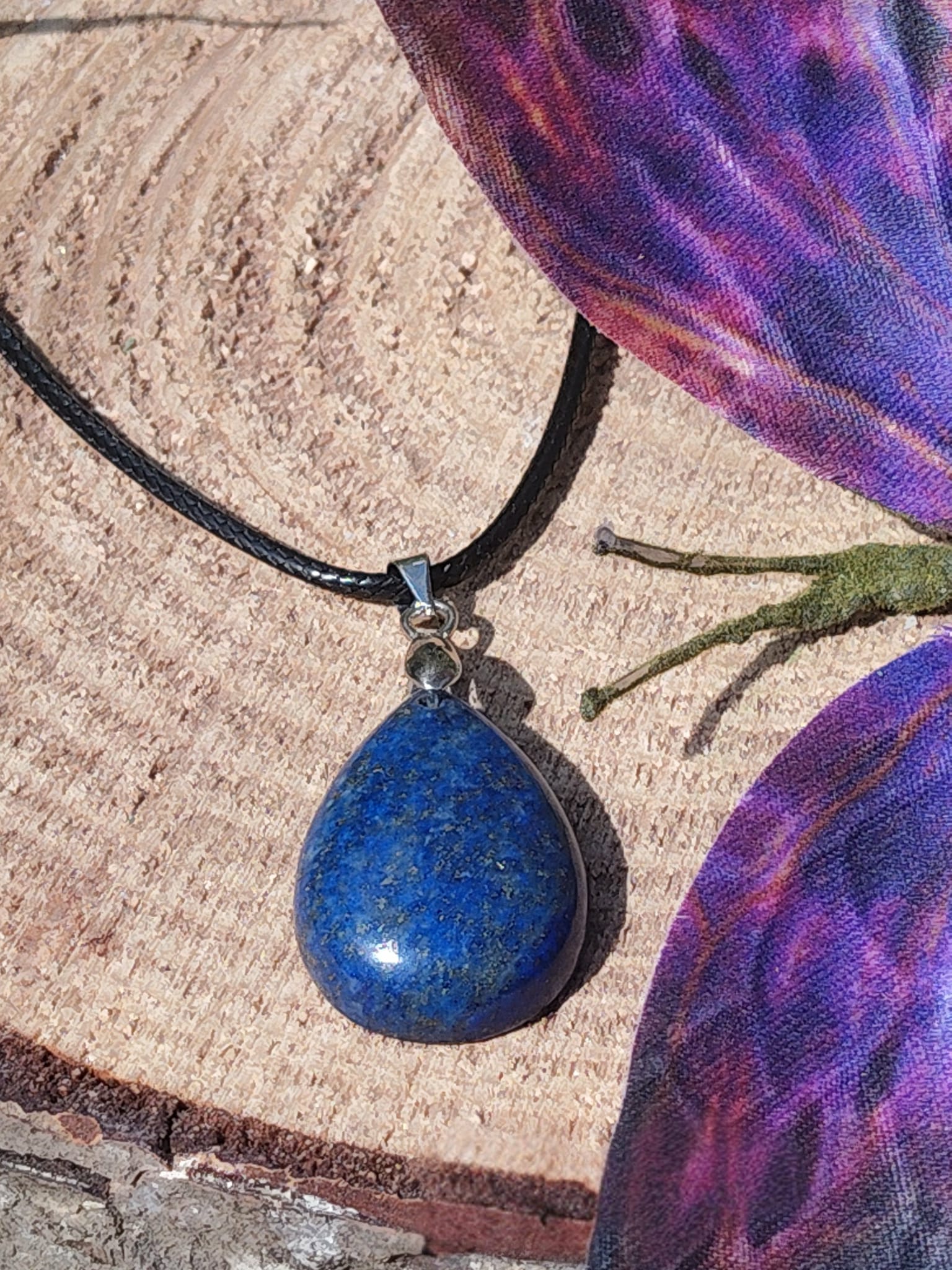 Pendentif goutte en lapis lazuli bleu sur bois avec papillon violet, collier en pierre naturelle lié à la confiance douce, à l’intuition et à l’apaisement mental.