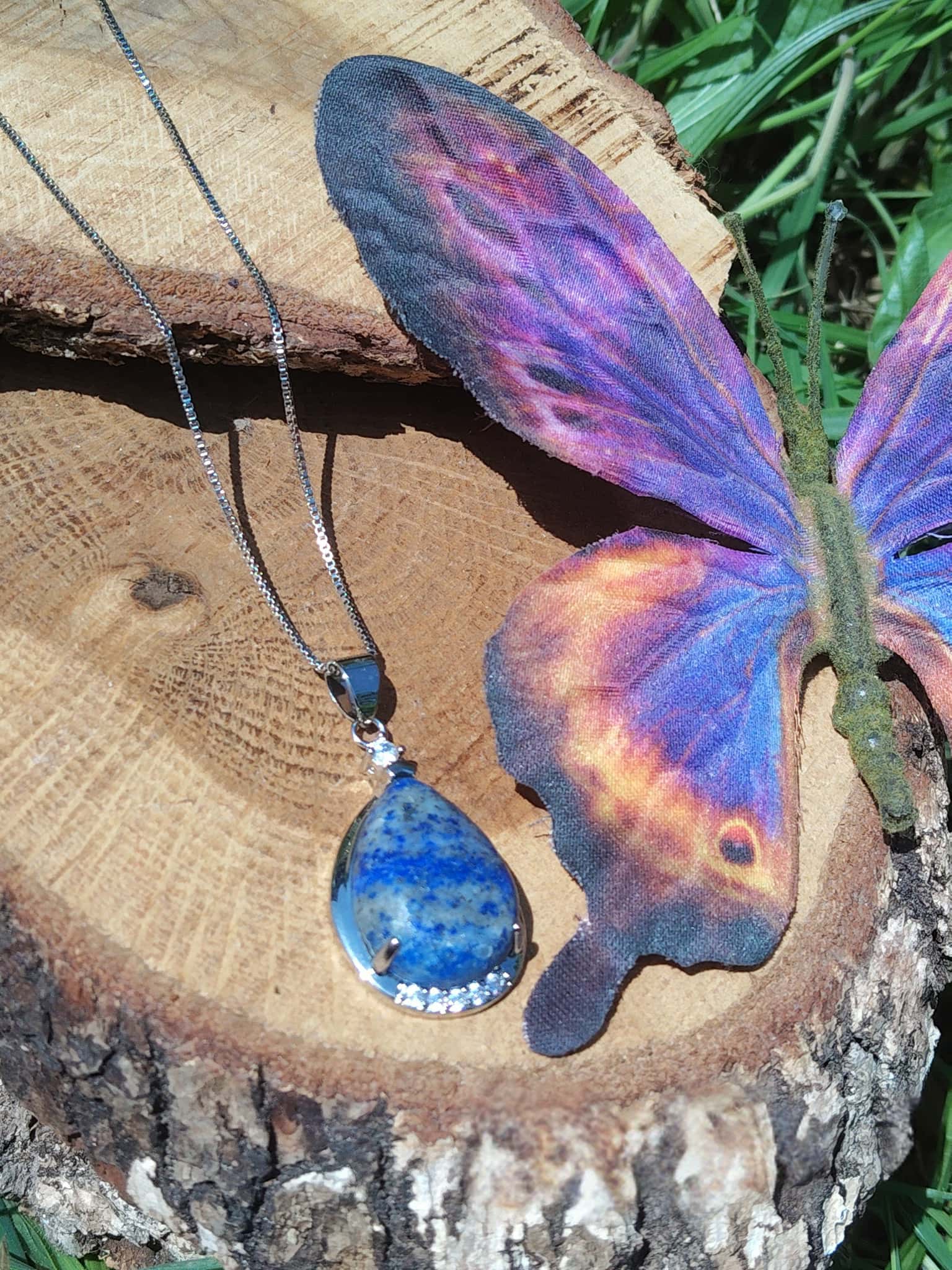 Collier goutte en lapis lazuli posé sur bois, bijou en pierre naturelle évoquant le calme des pensées, la parole fluide et la présence à soi.