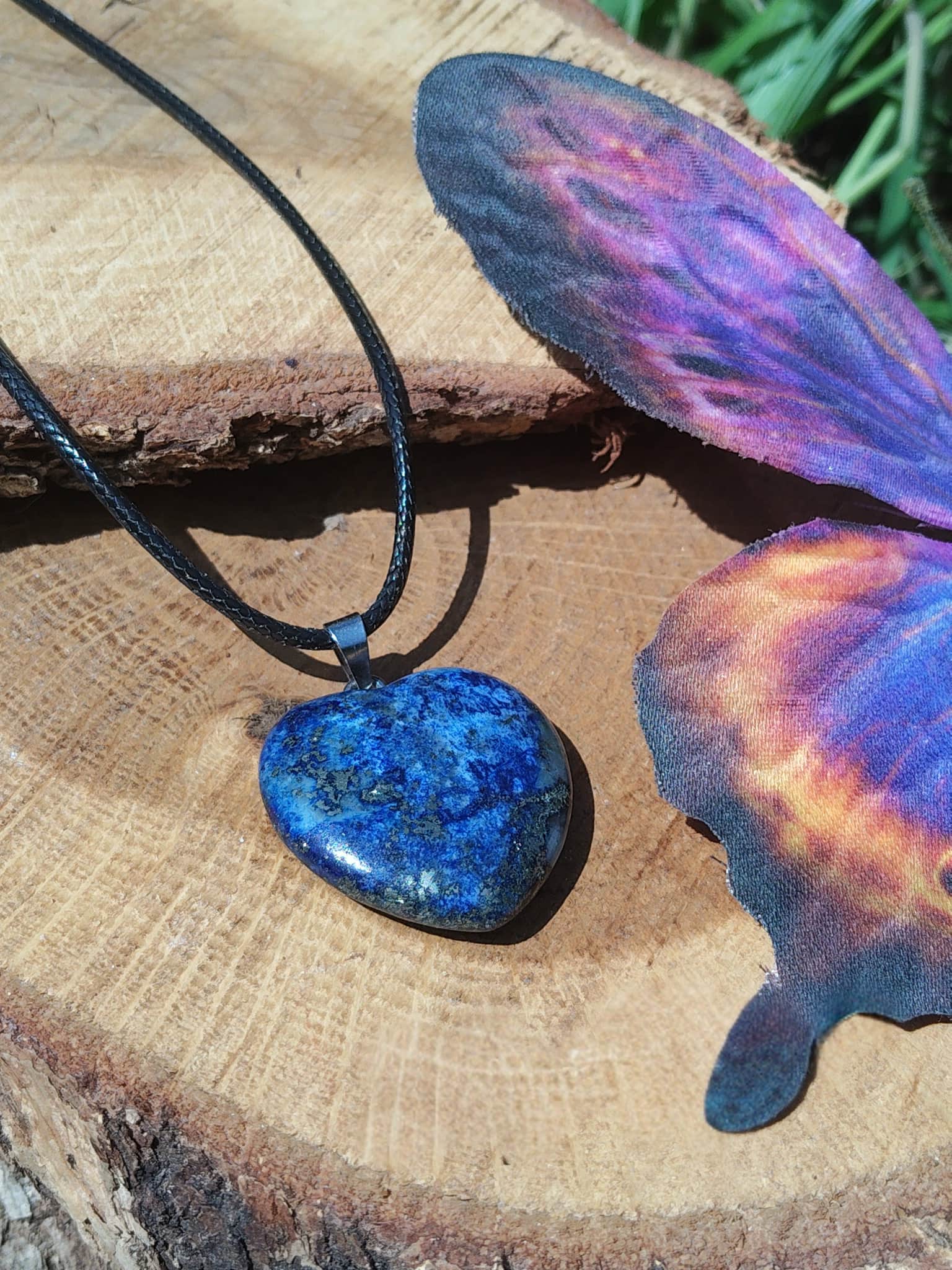 Pendentif cœur en lapis lazuli bleu sur bois avec aile de papillon colorée, collier en pierre naturelle lié à l’inspiration, à l’écoute de soi et à l’harmonie intérieure.