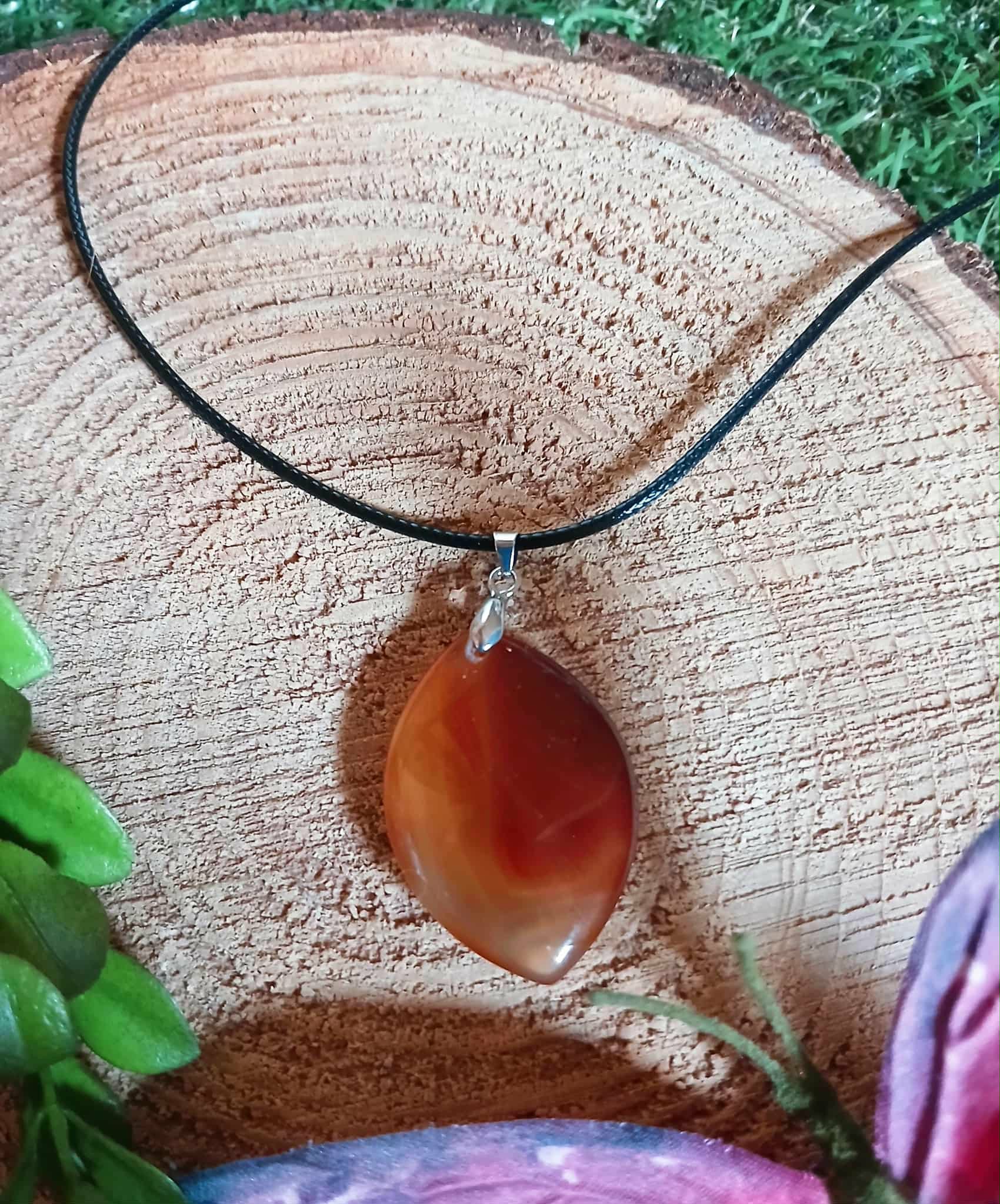 Pendentif Cornaline naturelle suspendu devant une géode blanche, bijou orange lié au chakra sacré pour vitalité, créativité et concentration