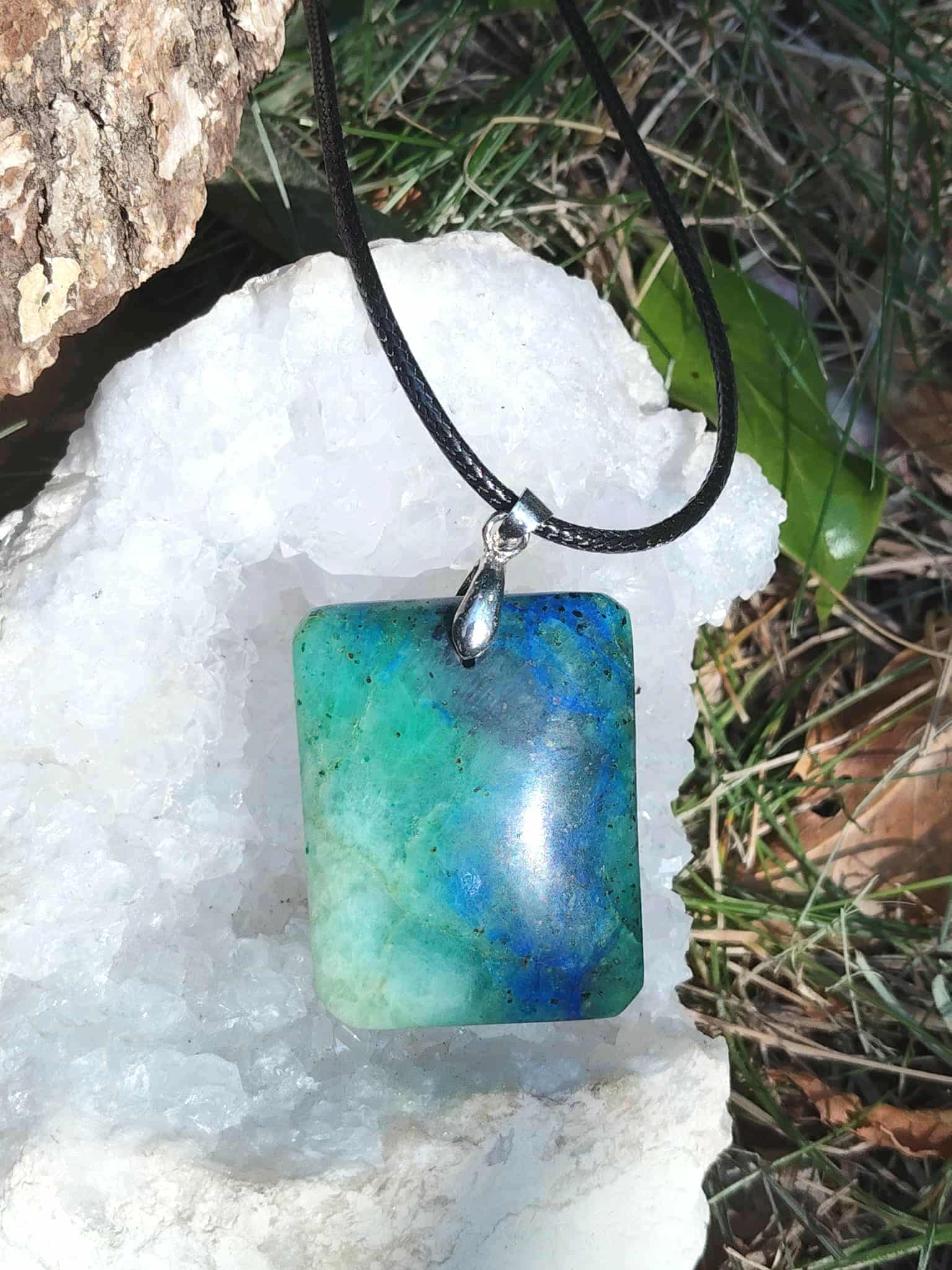 Pendentif azurite chrysocolle rectangulaire bleu vert sur cordon noir, posé sur géode en décor naturel, pierre naturelle associée au recentrage, à la sérénité et à l’expression apaisée.