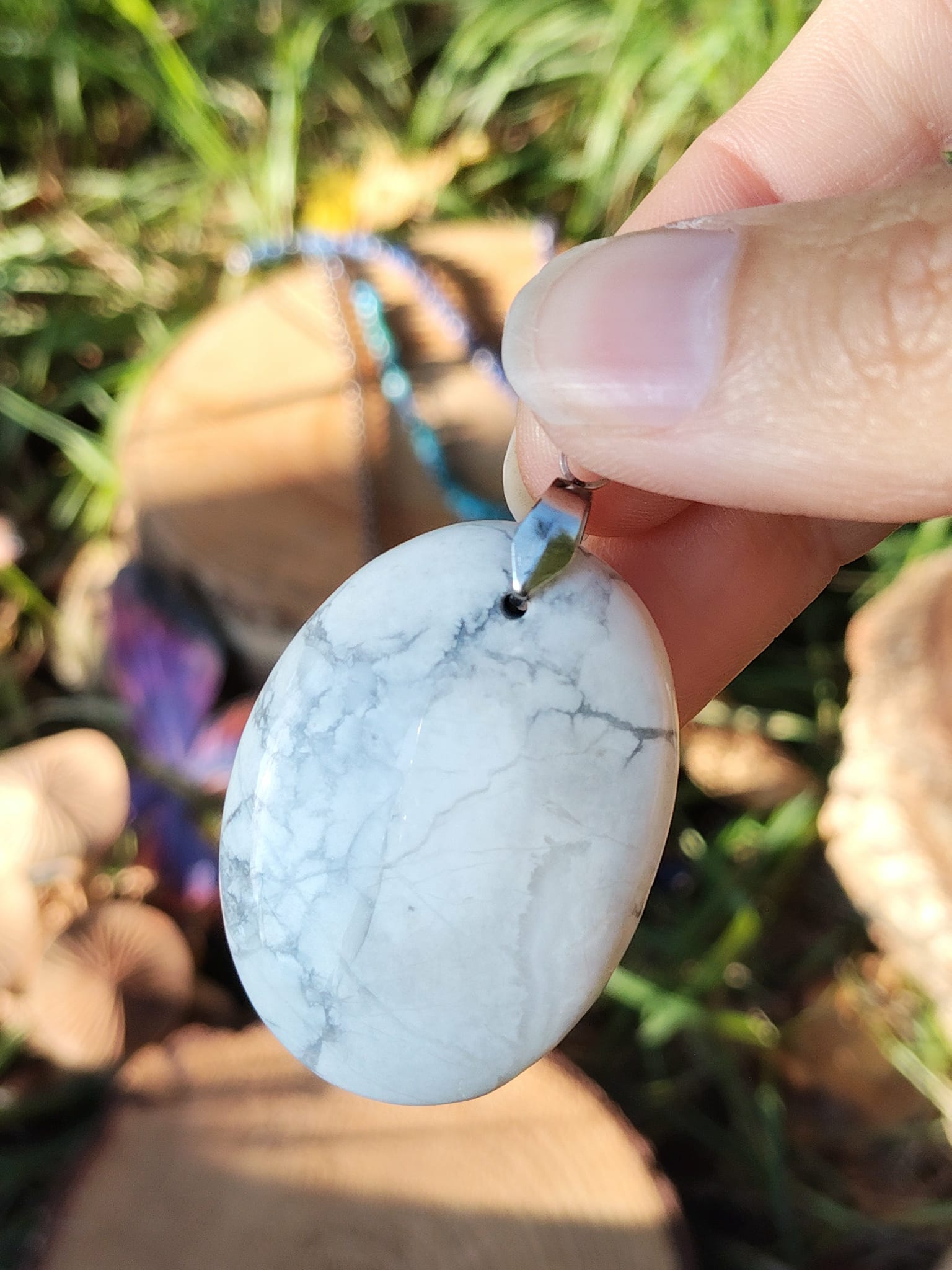 Pendentif howlite blanche tenu dans la main, pierre naturelle pour lâcher-prise, douceur du cœur et état d’esprit plus posé