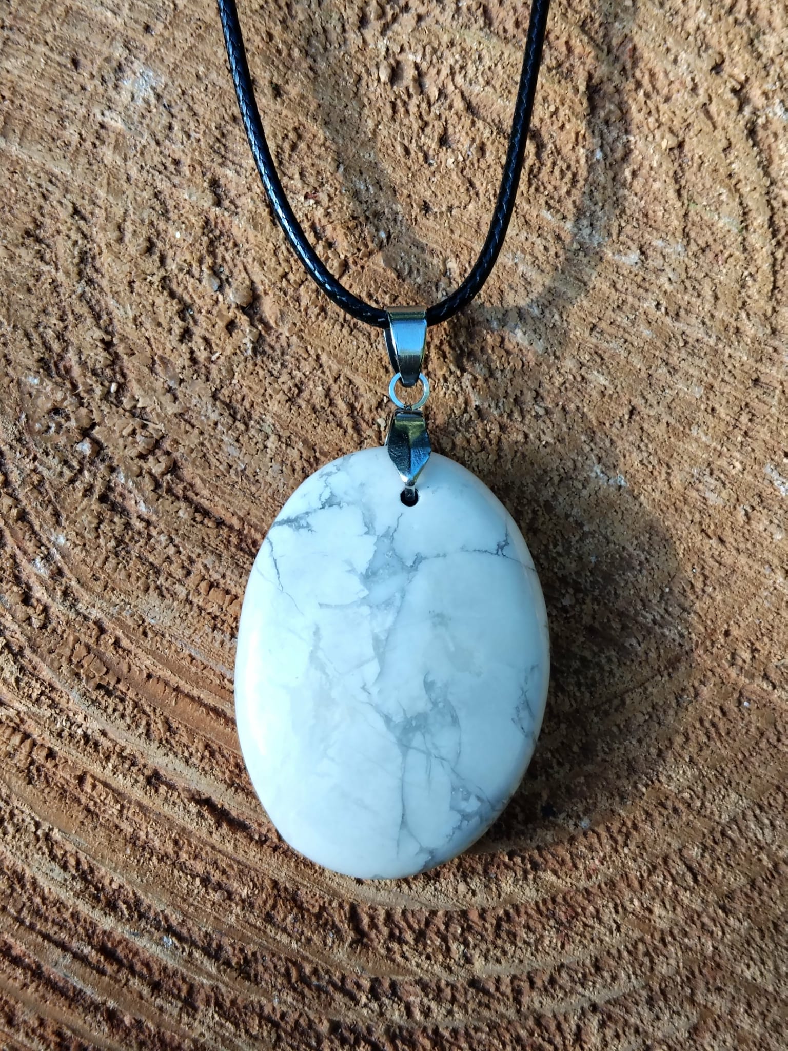 Pendentif howlite blanche sur cordon noir, posé sur bois, harmonisation émotionnelle, lâcher-prise et sensation de paix intérieure
