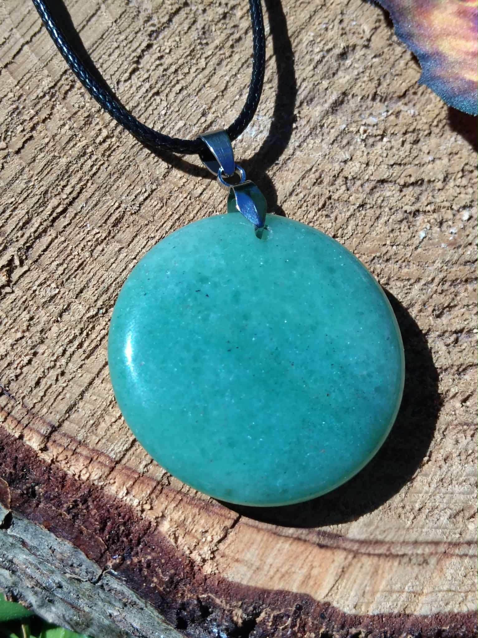Pendentif aventurine verte en pierre naturelle posé sur tranche de bois, confiance en soi, passage à l’action et stabilité intérieure