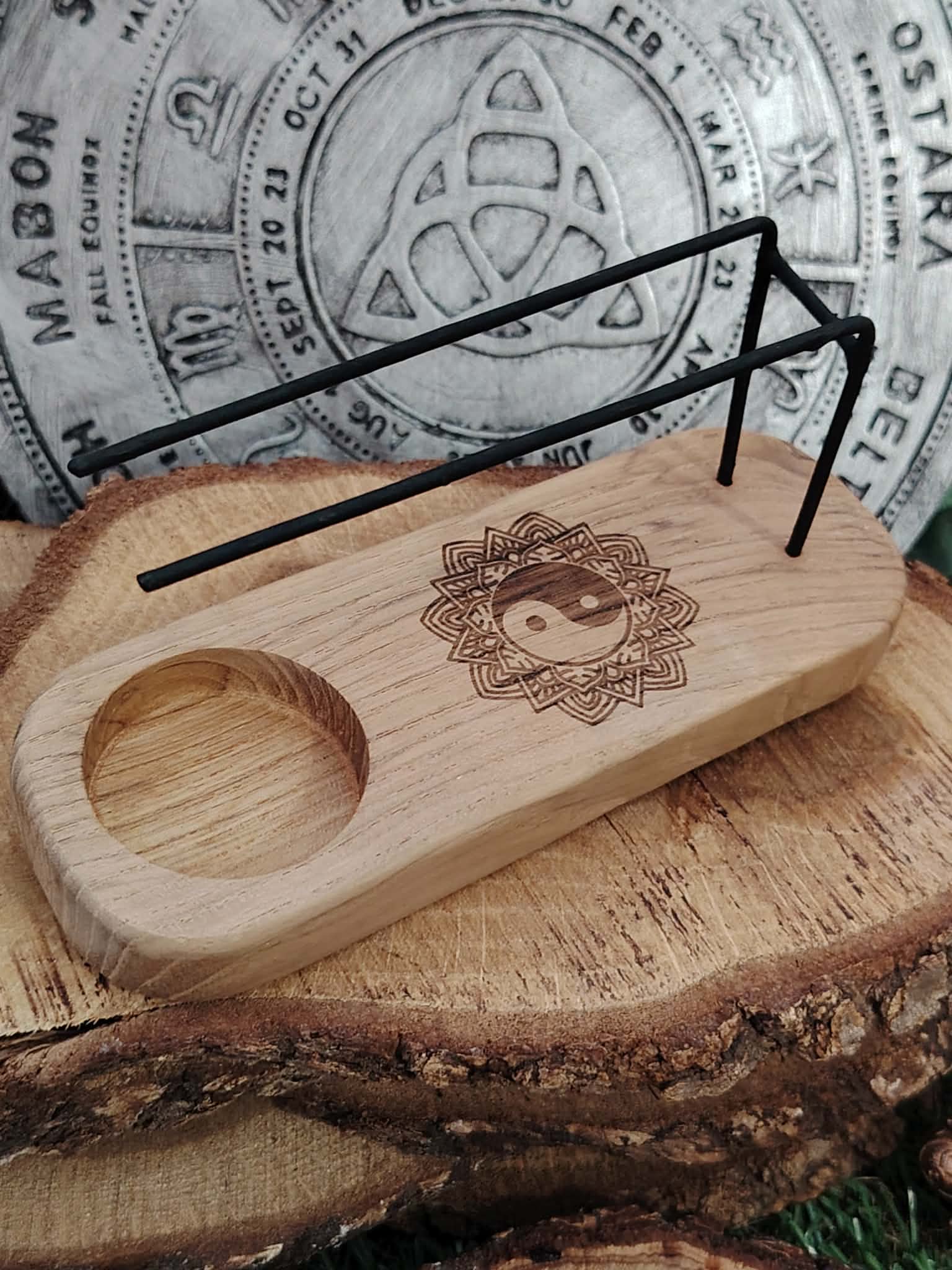 Porte palo santo en bois gravé Yin Yang, posé sur rondins de bois avec roue des sabbats triquetra en arrière-plan