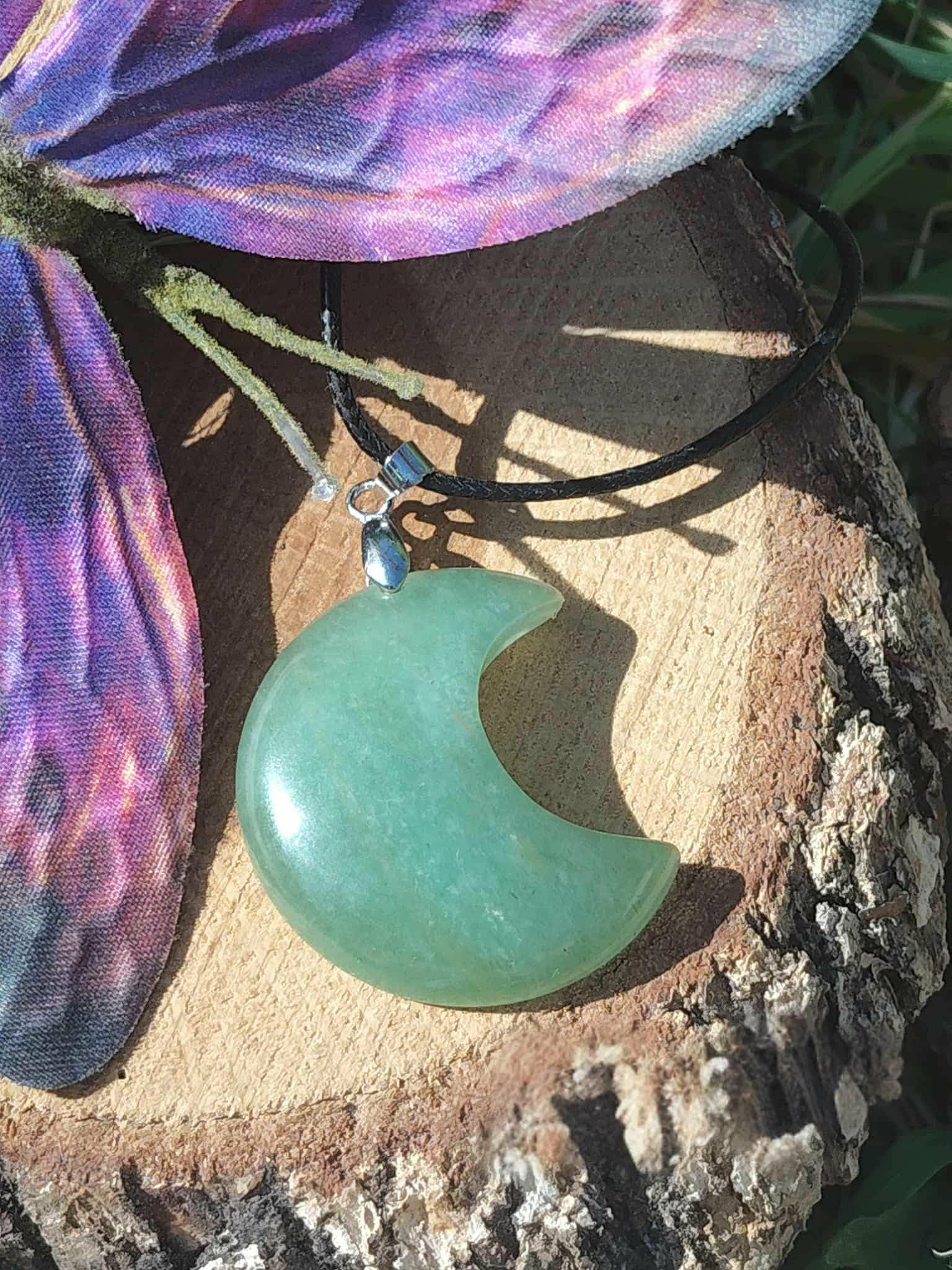 Pendentif lune en aventurine verte sur bois avec plume, bijou en pierre naturelle associé à l’apaisement, à l’ouverture du cœur et à la douceur intérieure.