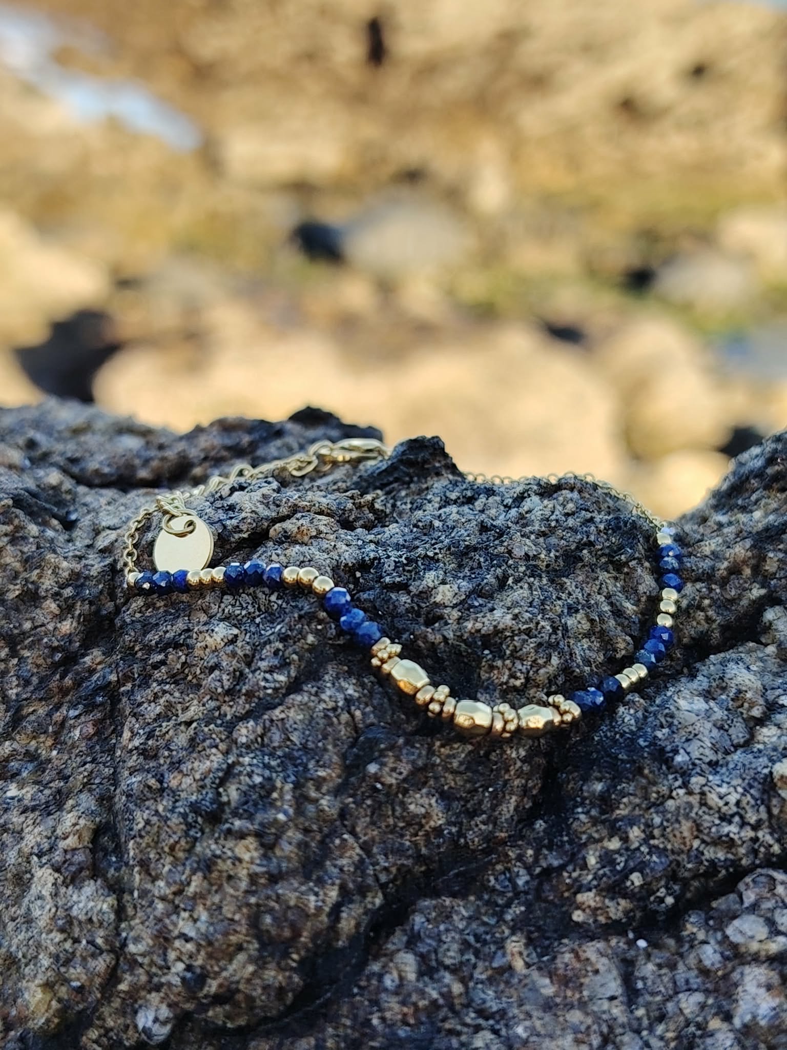 Bracelet lapis lazuli et acier inoxydable doré, bijou fin élégant sur pierre grise, photo en extérieur