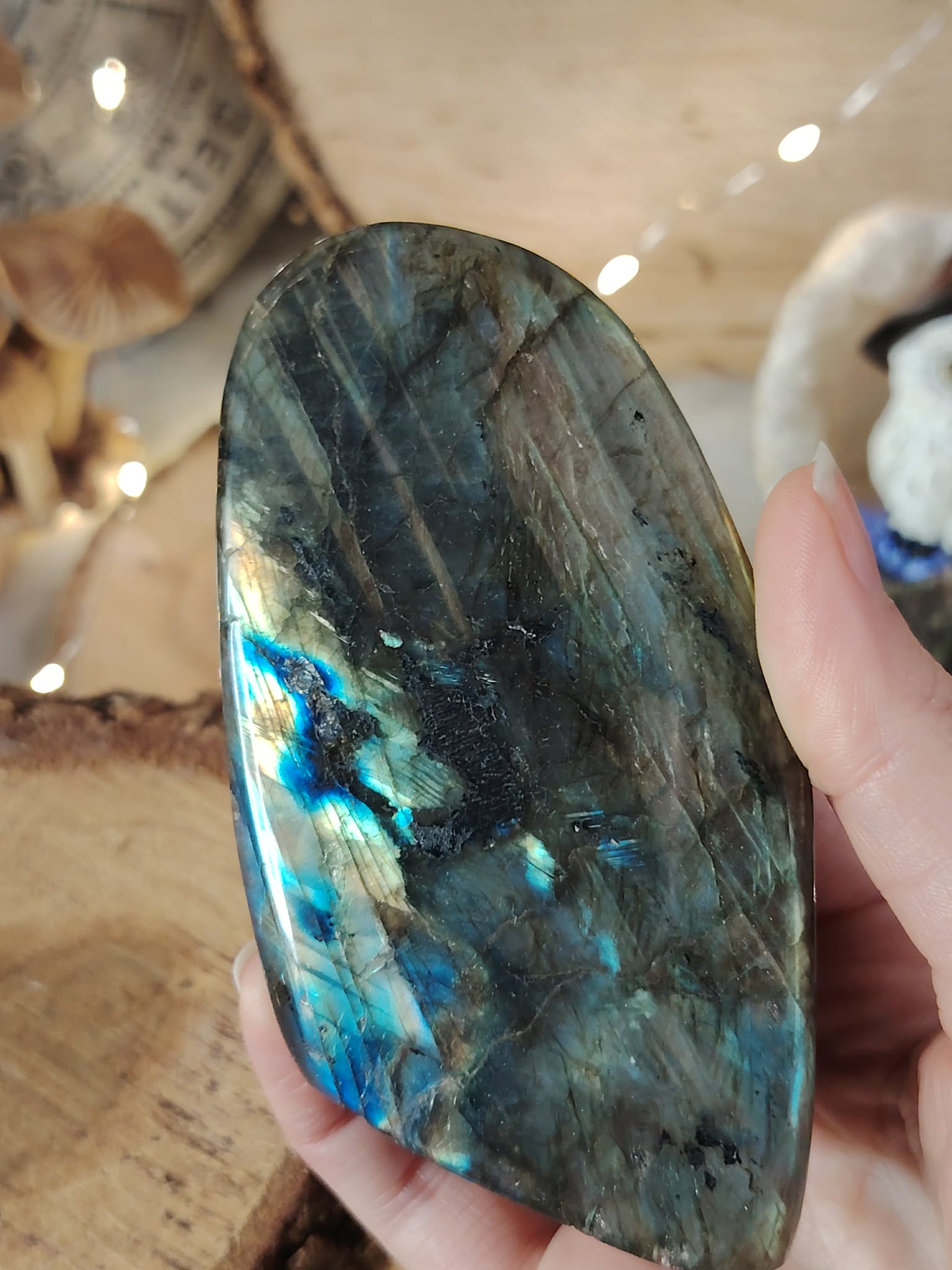 Labradorite forme libre tenue en main, reflets bleu-vert intenses et labradorescence visible, pierre naturelle liée au discernement, au recentrage et à l’équilibre intérieur.