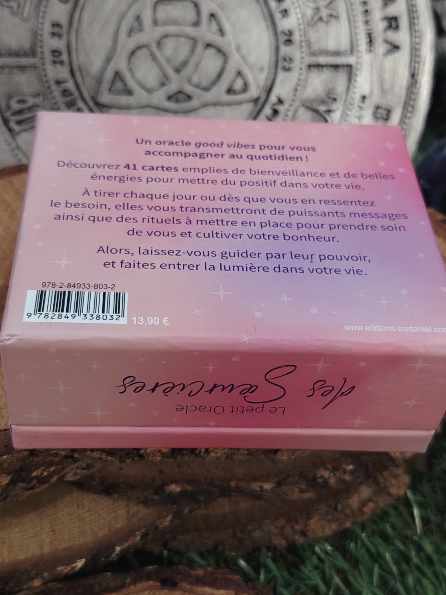 Dos du coffret Le Petit Oracle des Sœurcières (L’Atelier des Sœurcières) : boîte rose/violet avec texte de présentation et code-barres, posée sur rondin de bois, décor mandala ésotérique