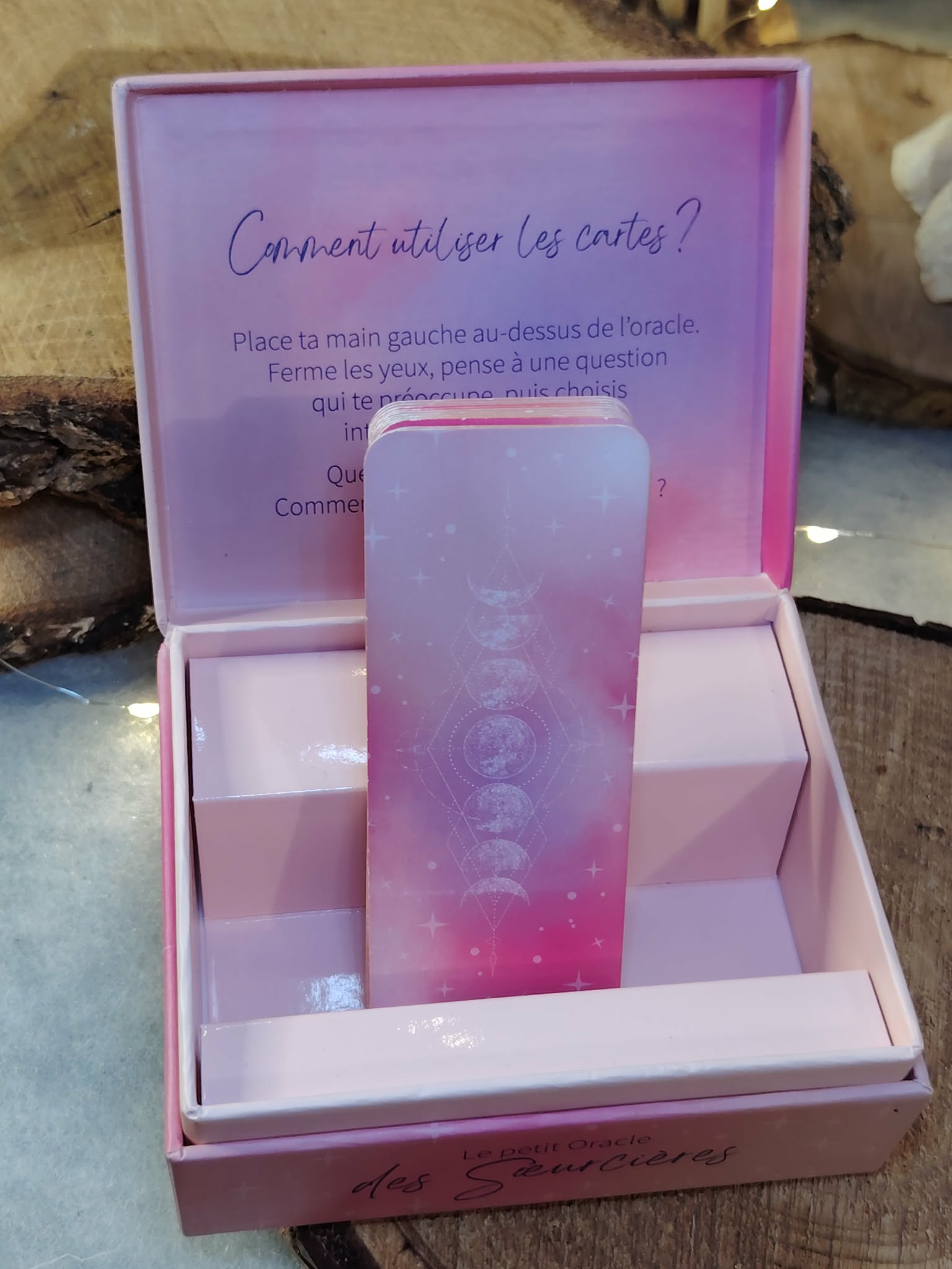 Le Petit Oracle des Sœurcières (L’Atelier des Sœurcières) : boîte ouverte avec cartes oracle rose/violet en français présentées debout, ambiance ésotérique sur support en bois